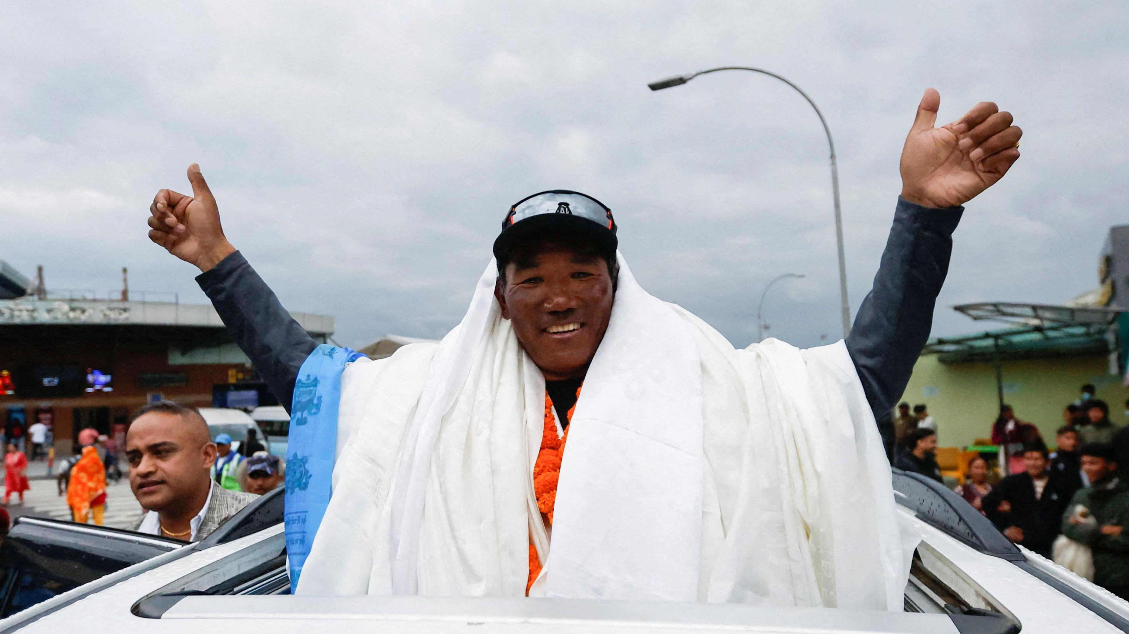 Kami Rita Sherpa waves to supporters from the top of car after arriving back at base camp after his 28th climb in 2023