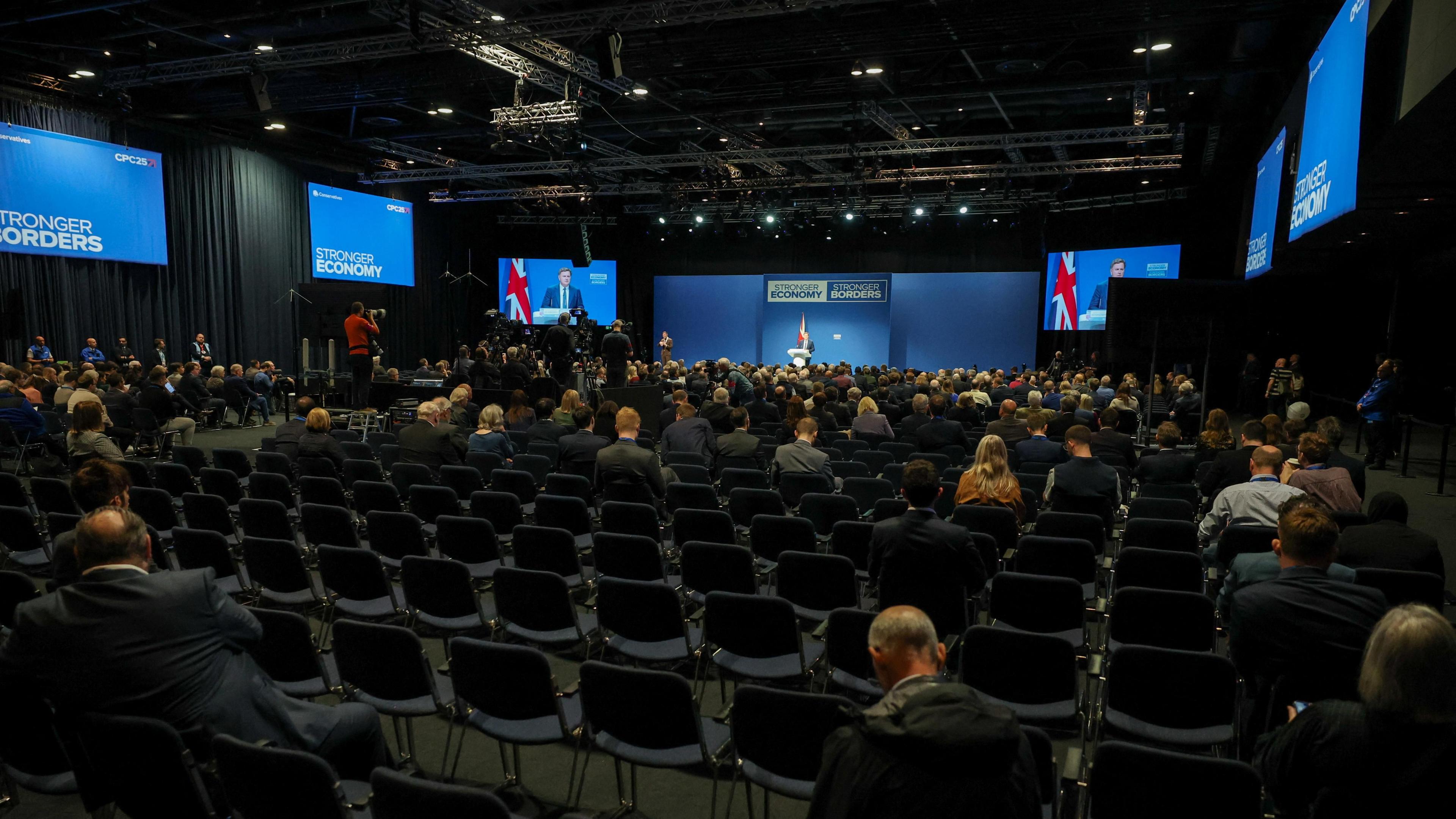 The auditorium for the Conservative Party conference in Manchester. In the foreground, a number of empty seats, as Mel Stride, the shadow chancellor, speaks to audience.