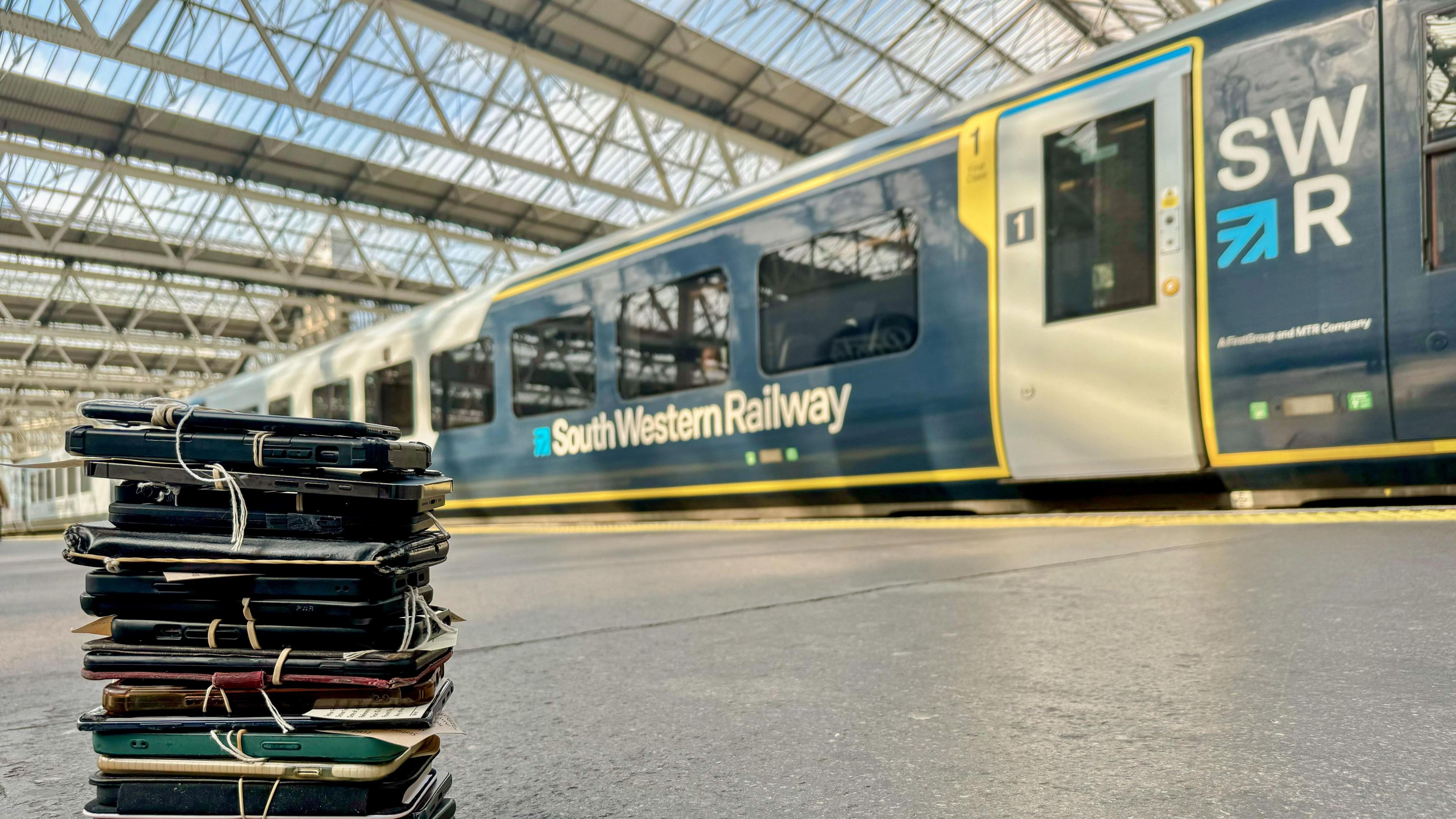 A stack of phones on a train platform. In the background is an SWR train.