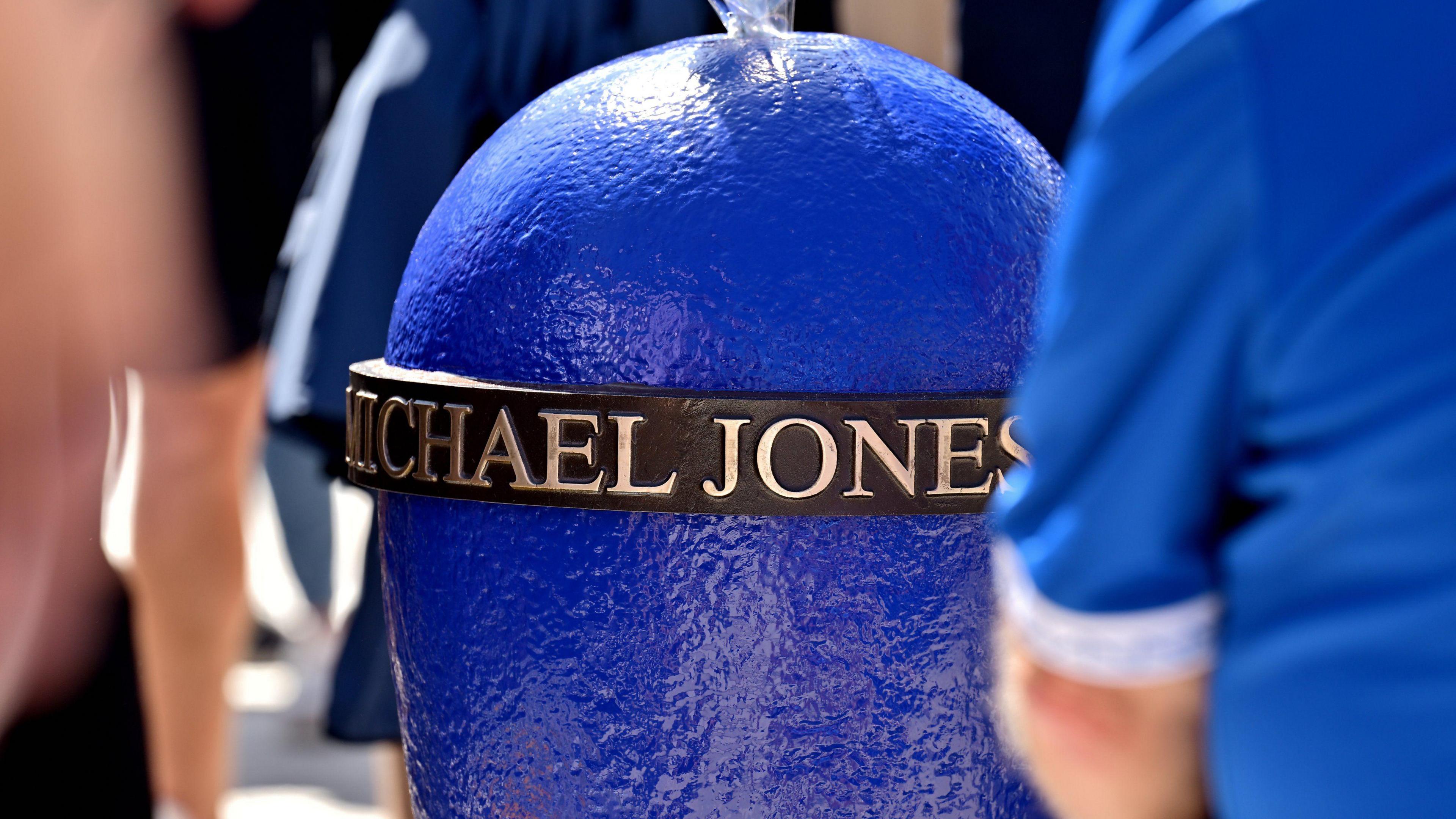 A mooring post painted in royal blue with a bronze ring bearing Michael Jones' name