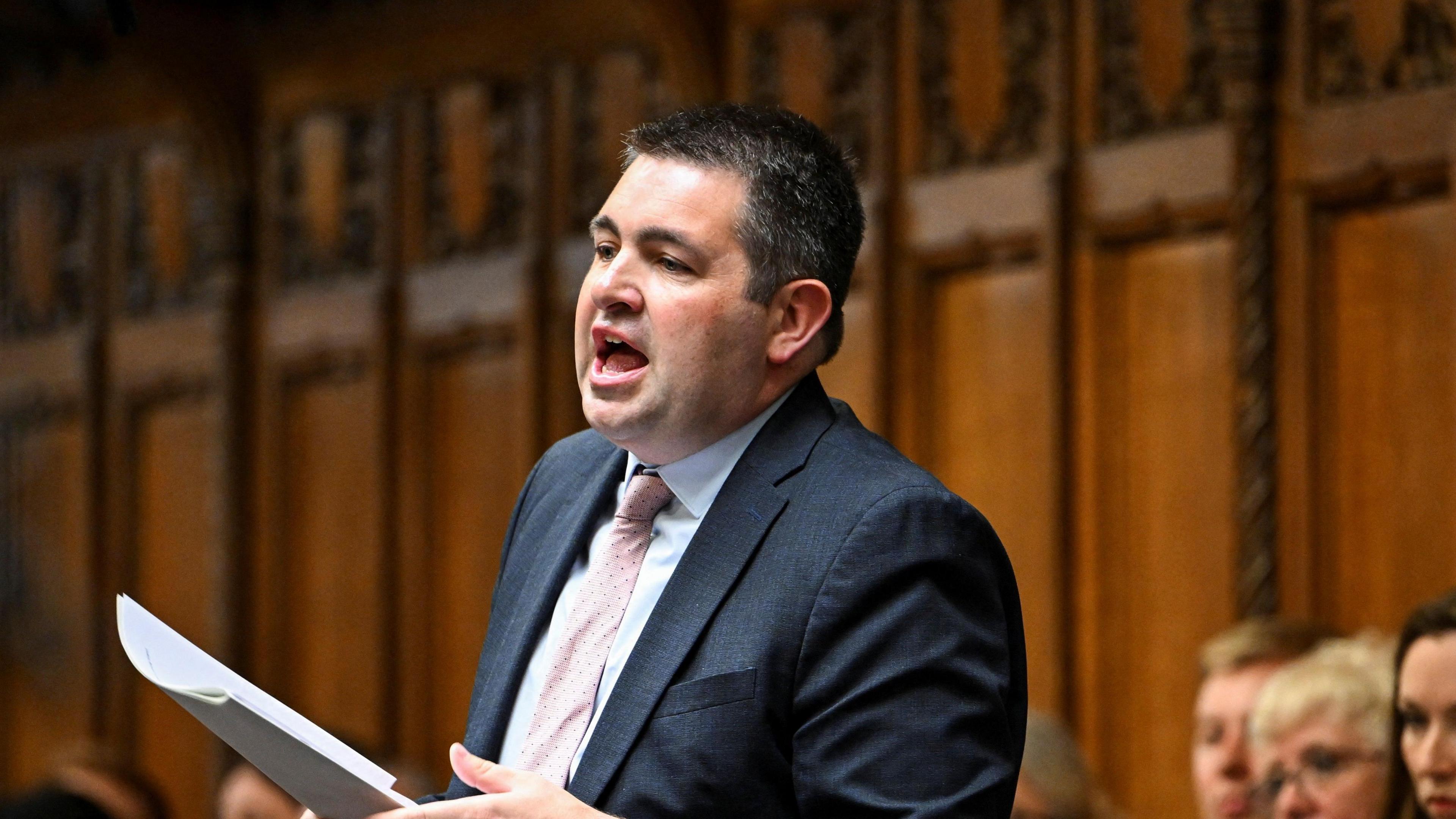 Shaun Davies MP, wearing a suit, addressing the House of Commons whilst holding notes