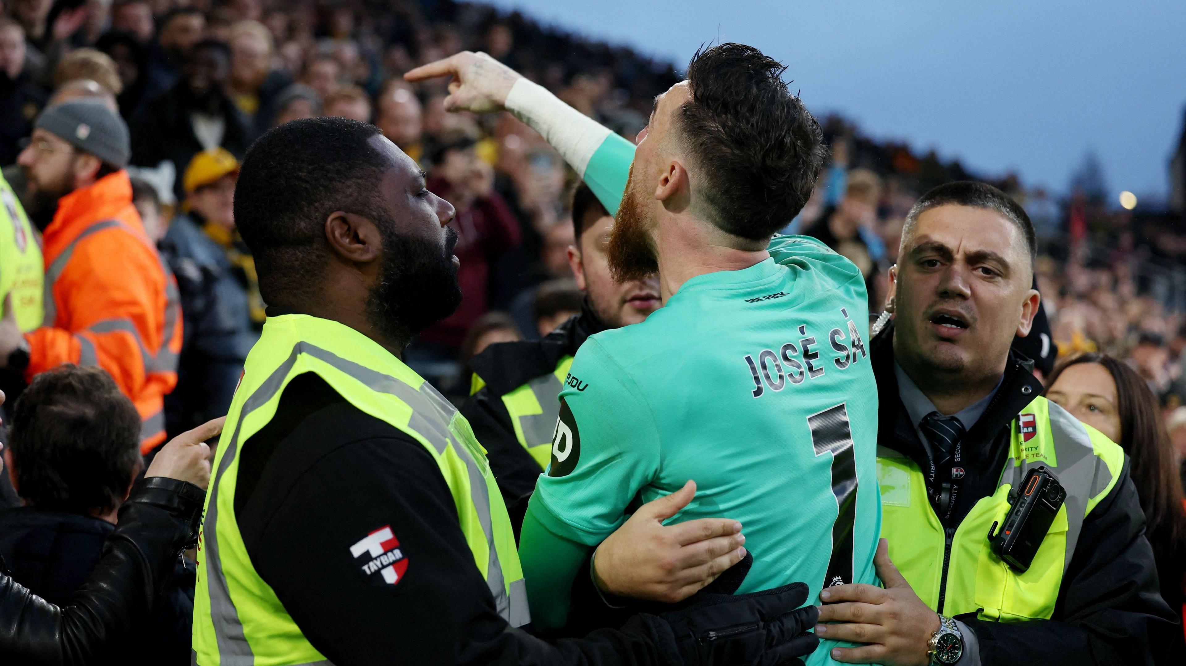 Jose Sa being held back by two stewards as he angrily confronts a Wolves supporter