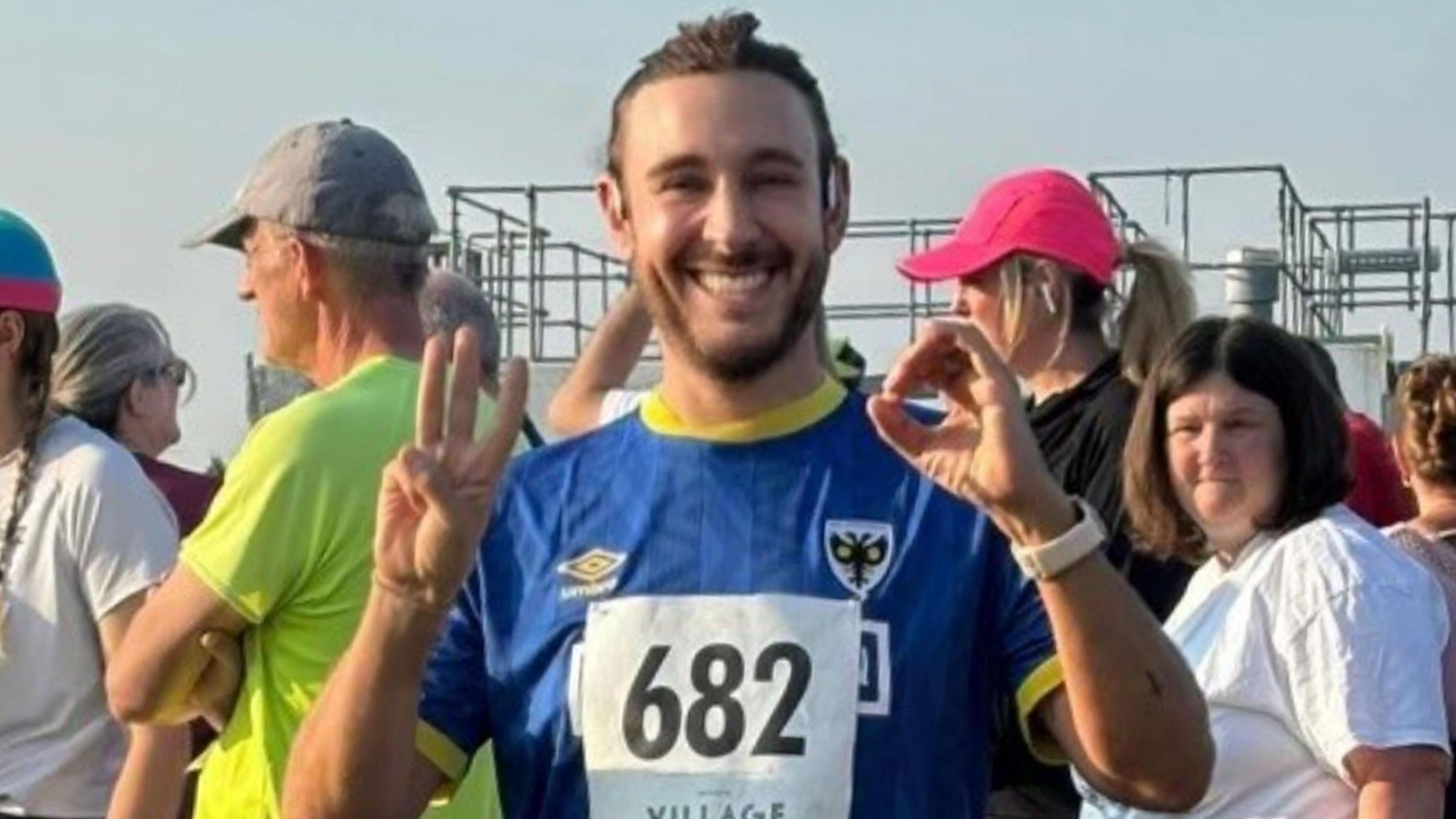 Wimbledon fan Graham Stacey signing '3-0' with his fingers while wearing a Dons kit