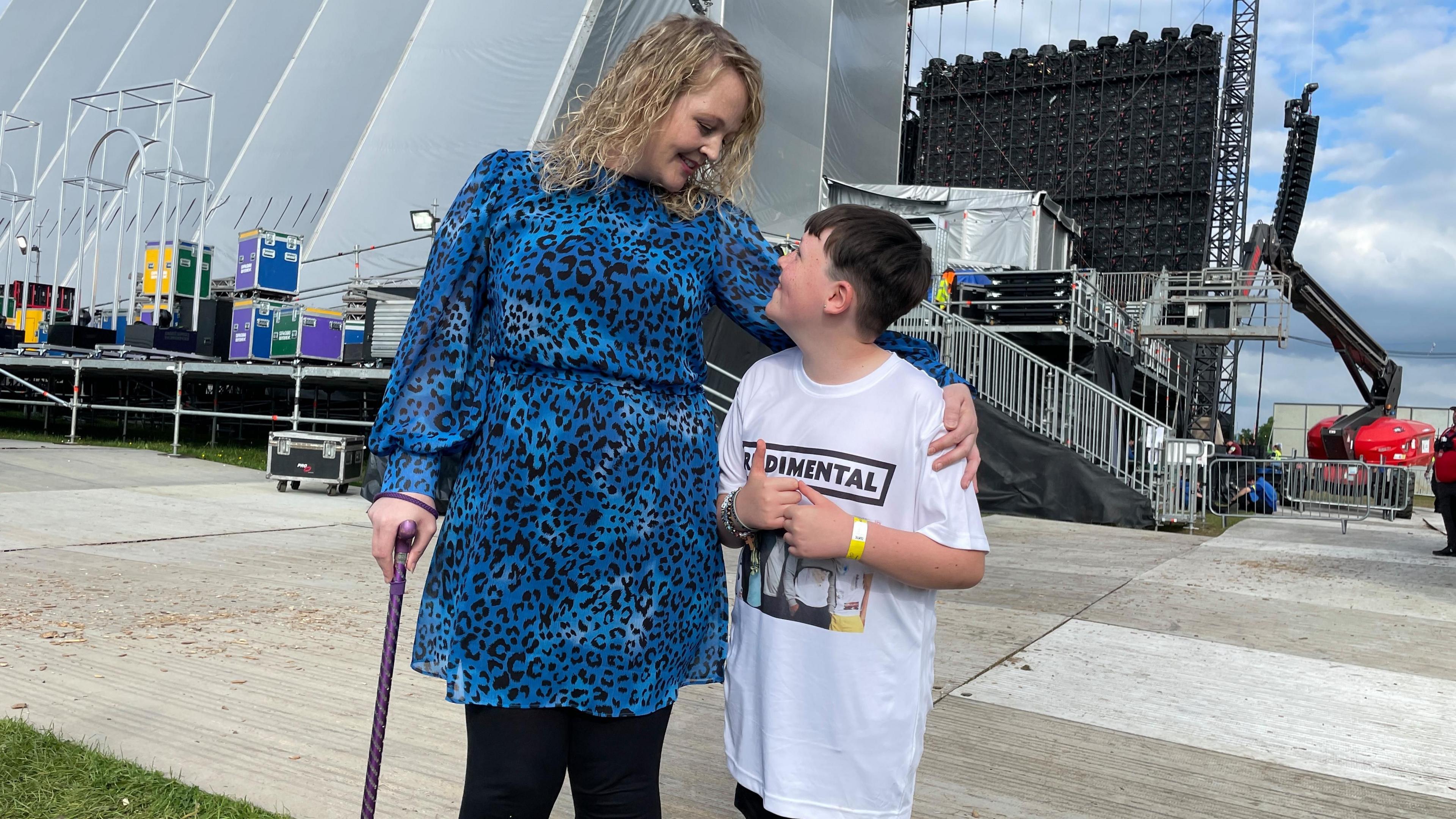 Josh and his mum smiling at each other behind the main stage at the festival