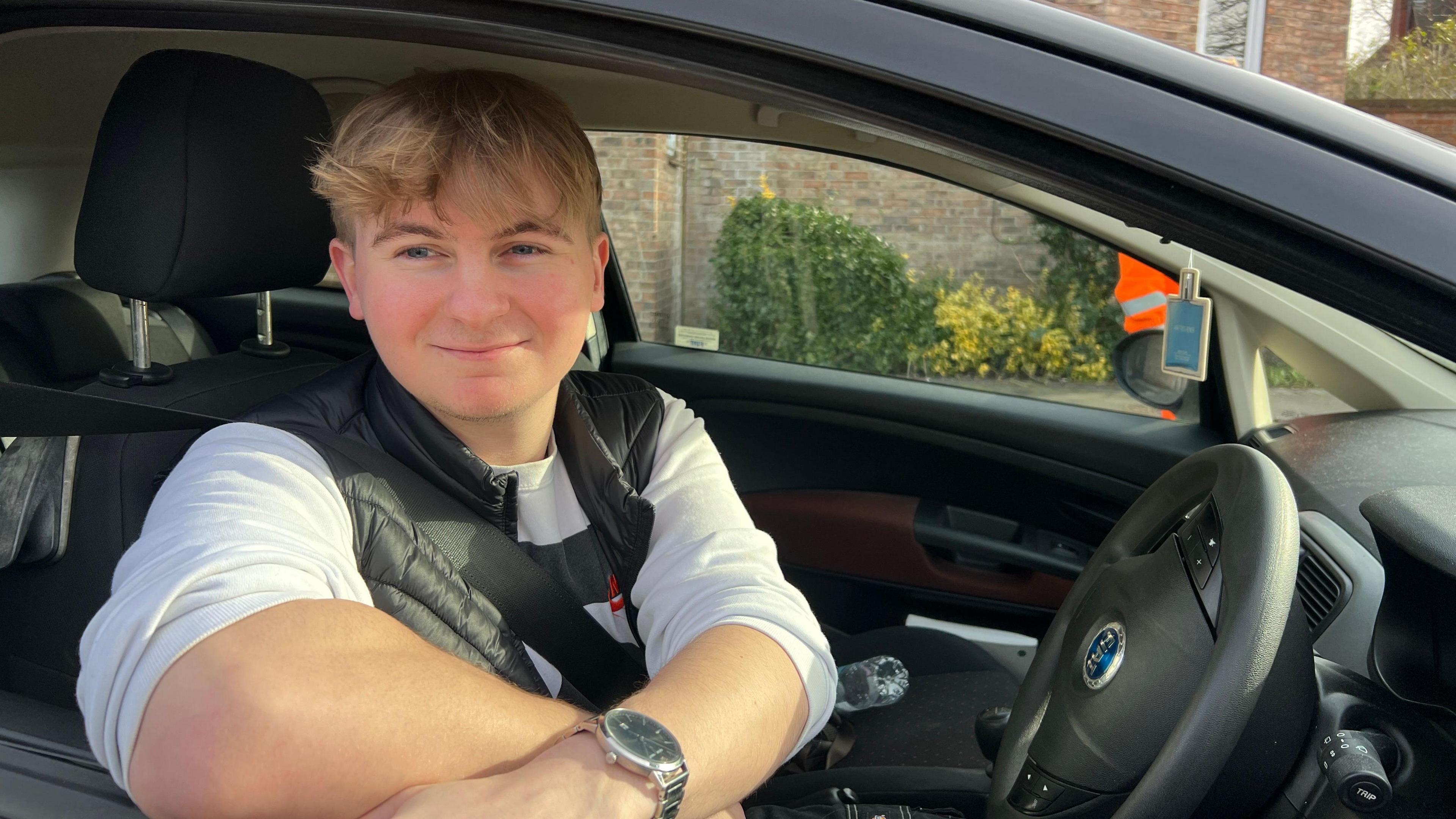 Charlie Manning is checking the charges at York's Marygate car park from the driver's seat of his car. He is wearing a white T-shirt, a black bodywarmer and a silver wristwatch.