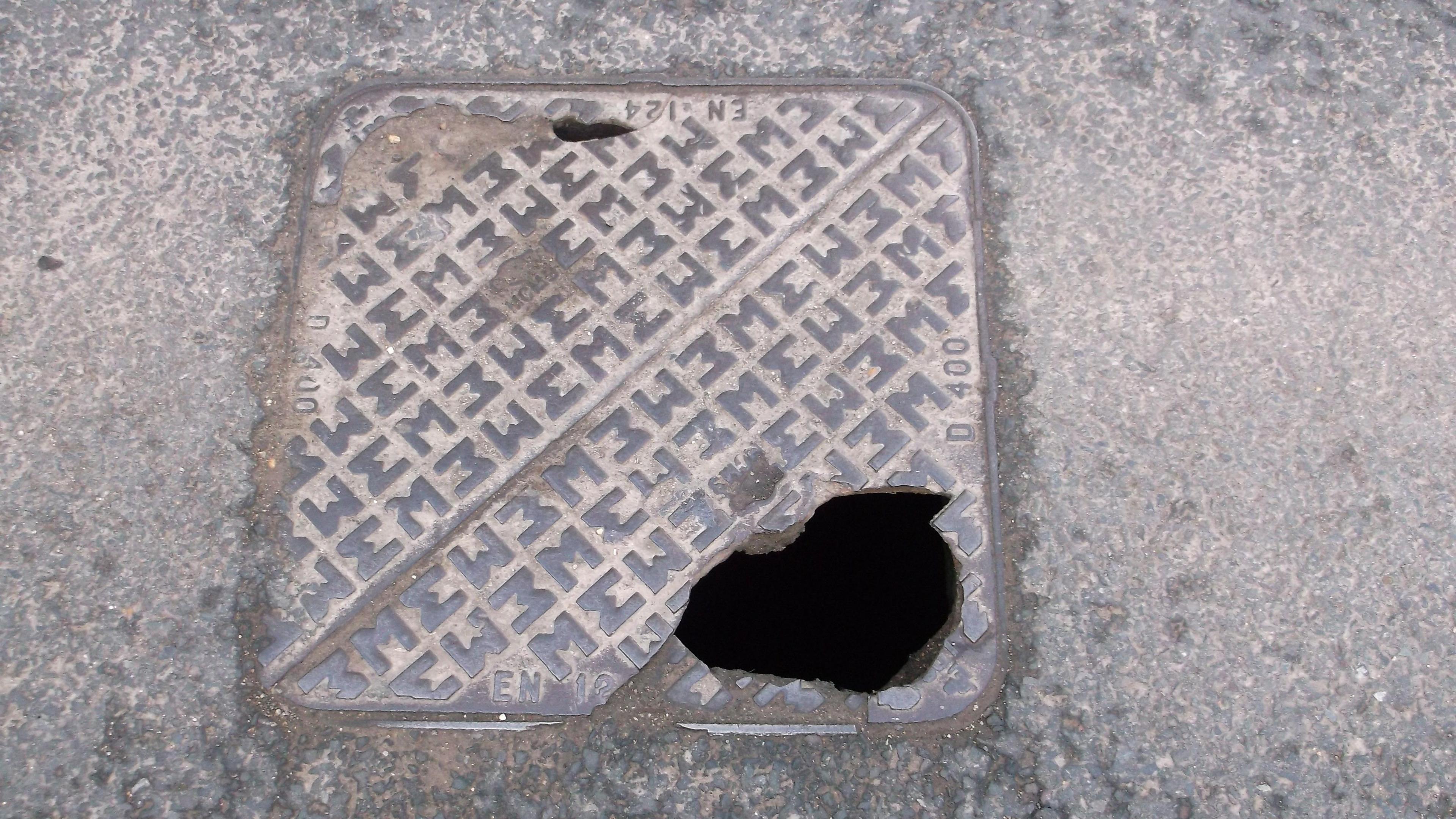 A metal man hole cover with a couple of holes in it.