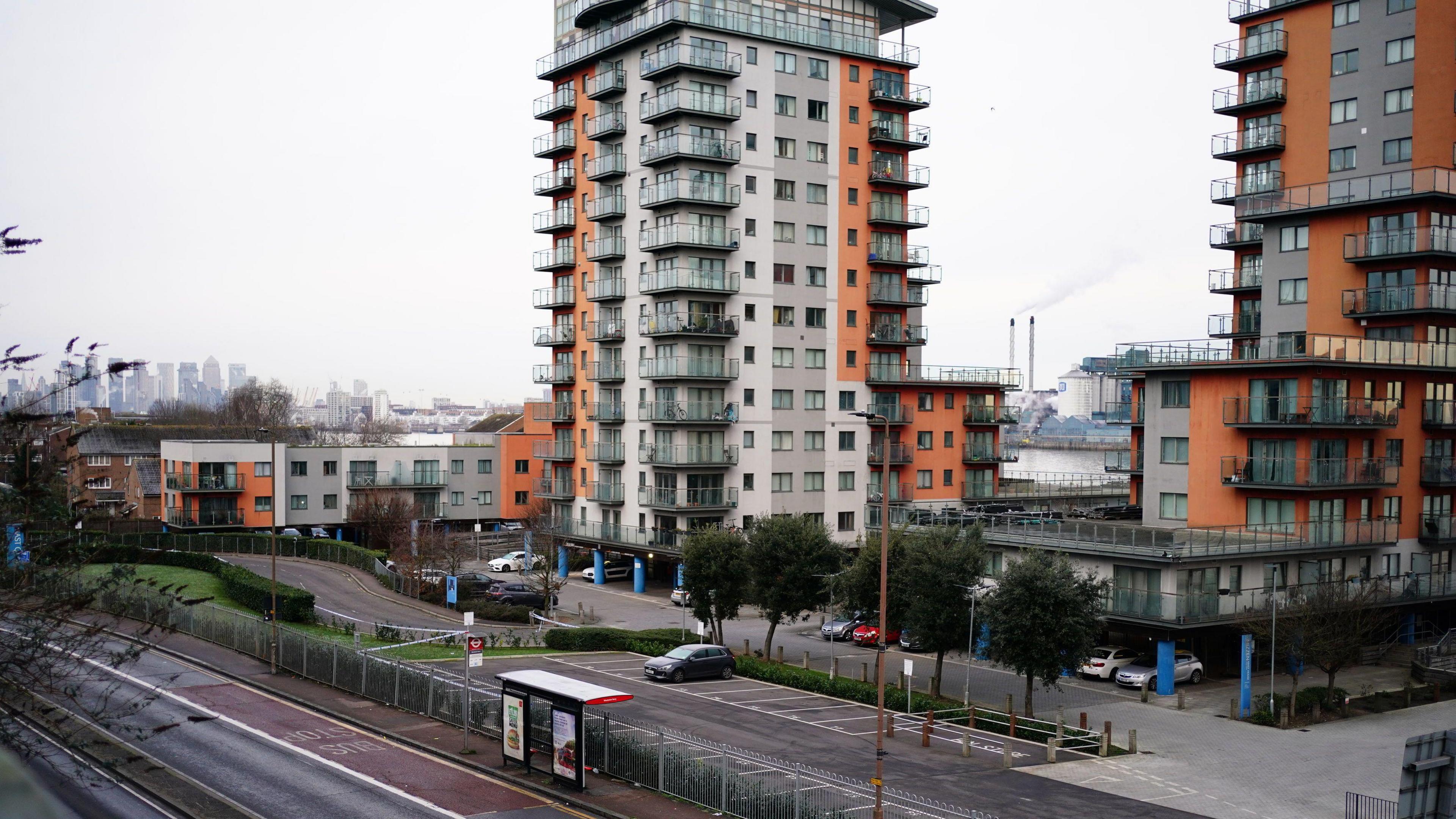 The bus stop on Woolwich Church Street where the boy was stabbed, photographed from a distance. It is on a road lined with blocks of flats.