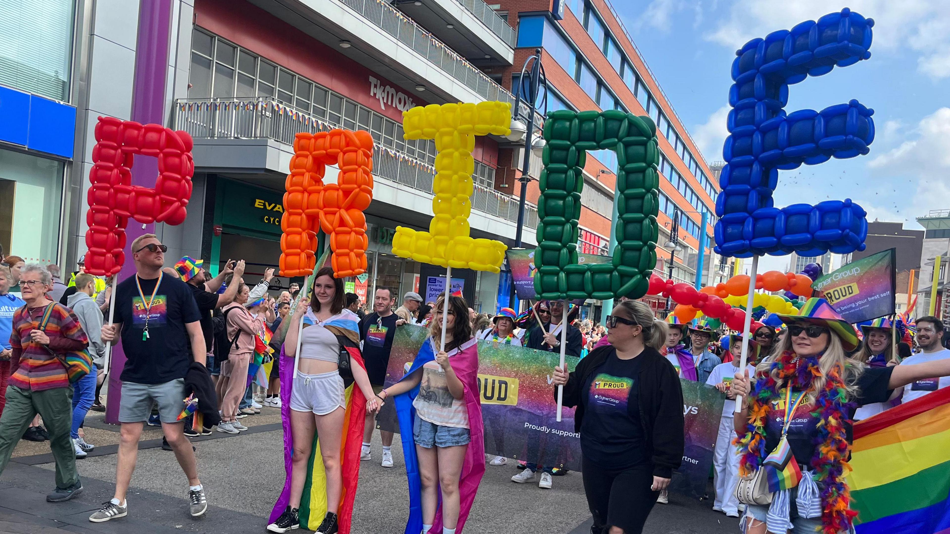 People holding up inflatable letters spelling out Pride.