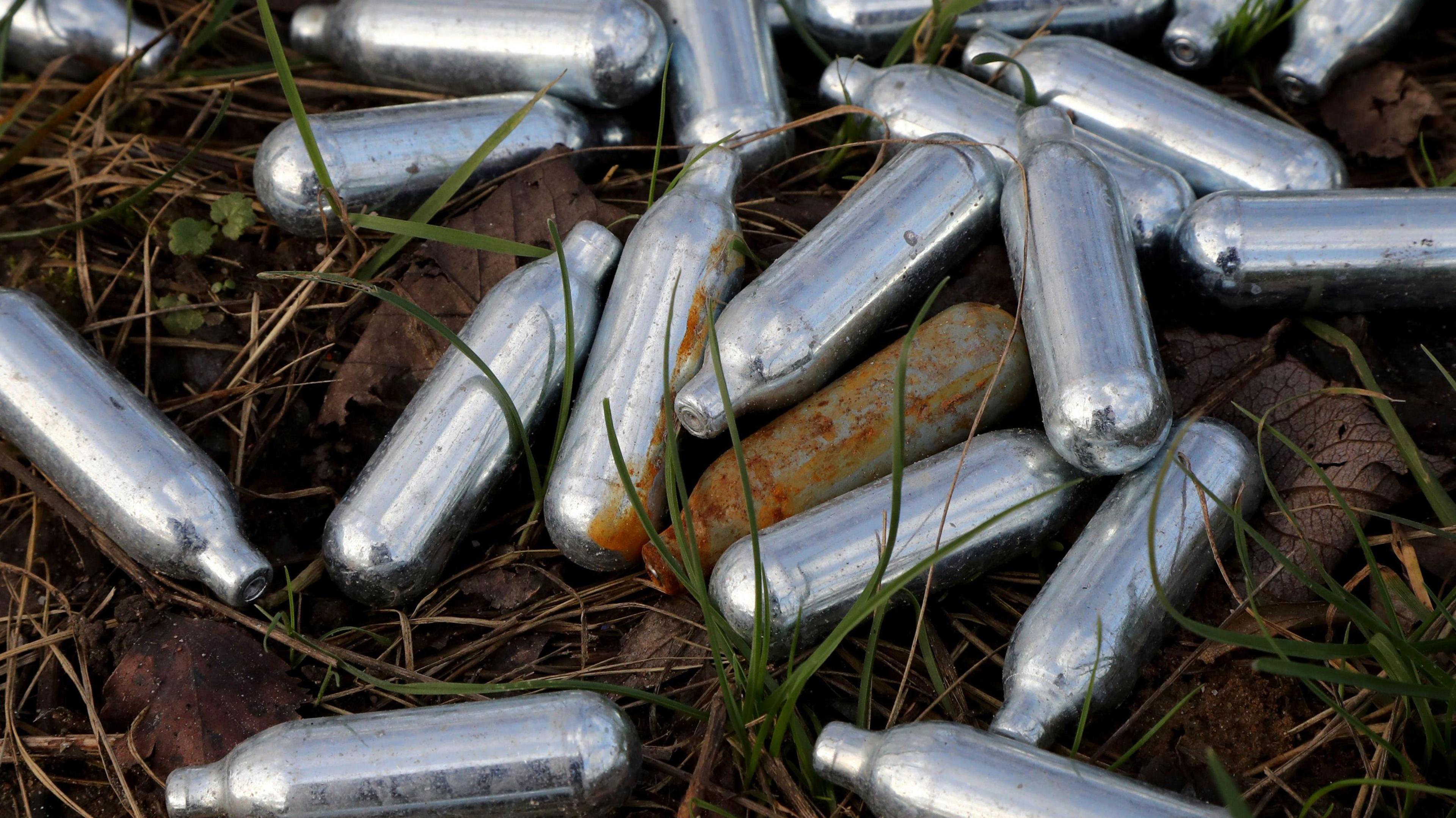 An image of small silver cannisters in grass.