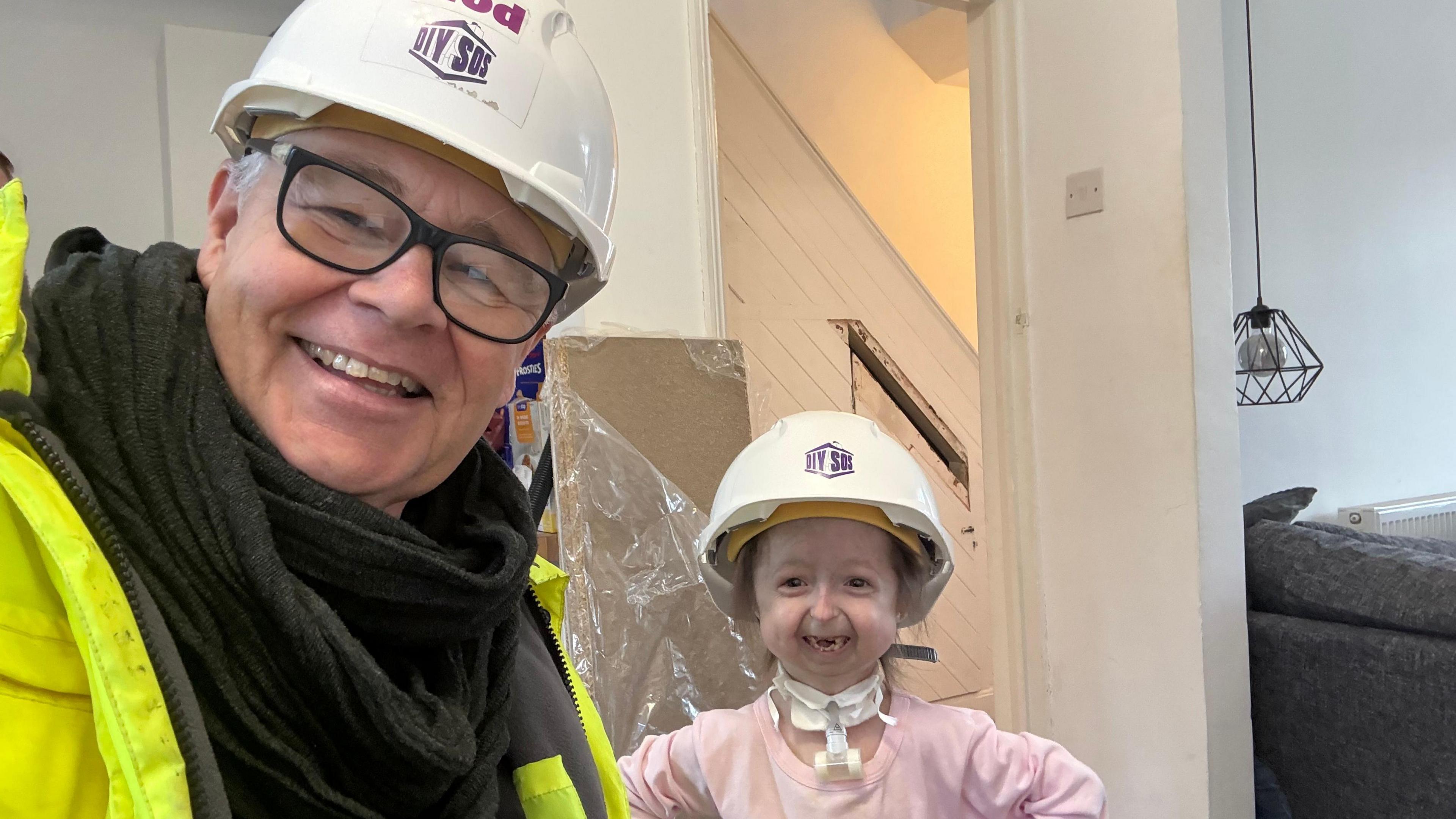 A selfie of Ian Hodgkinson in a high-vis jacket and white hard hat with Isla, also wearing a hard hat and smiling.