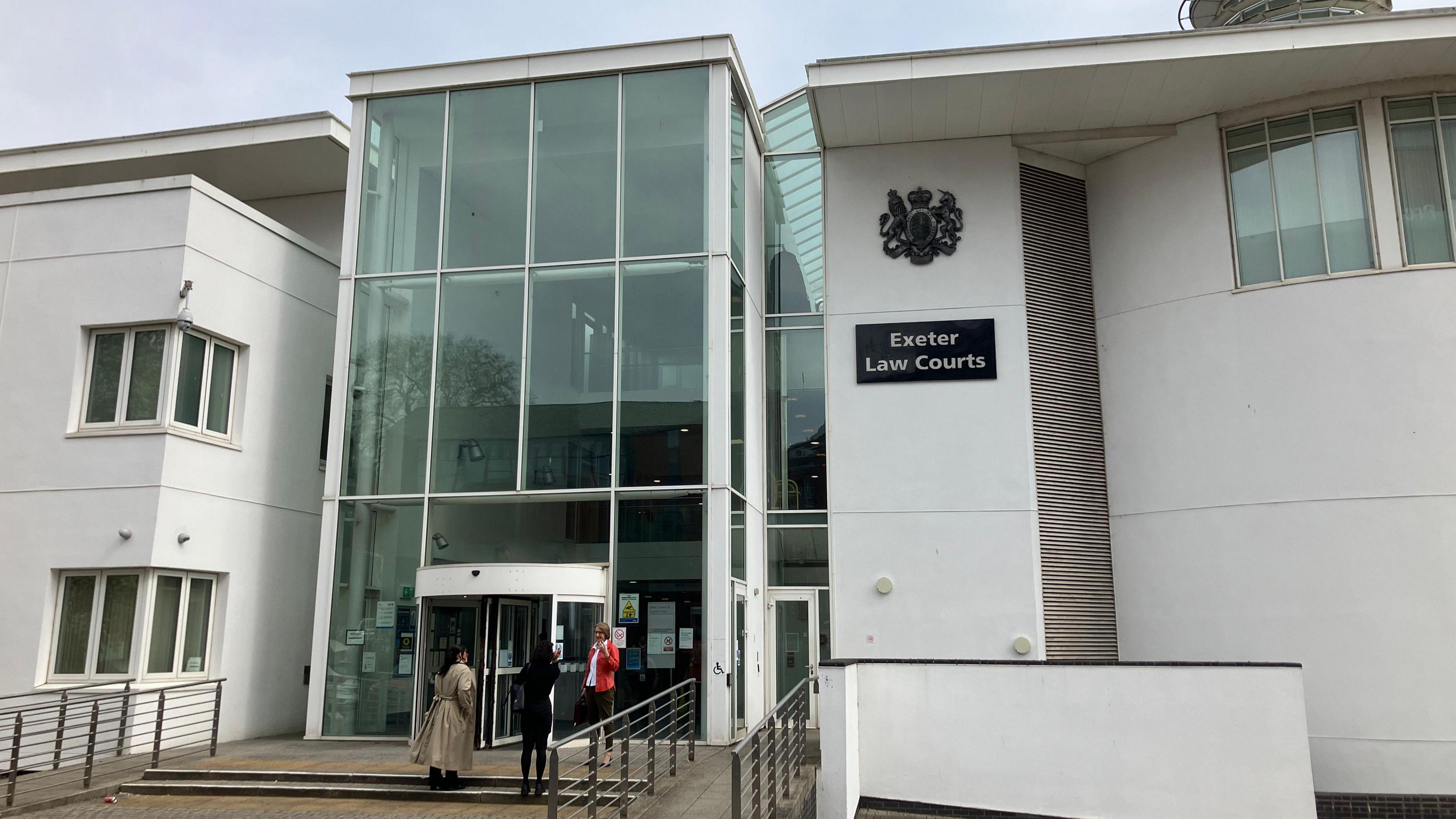 A white, modern court building with a glass entrance. A sign says "Exeter Law Courts".