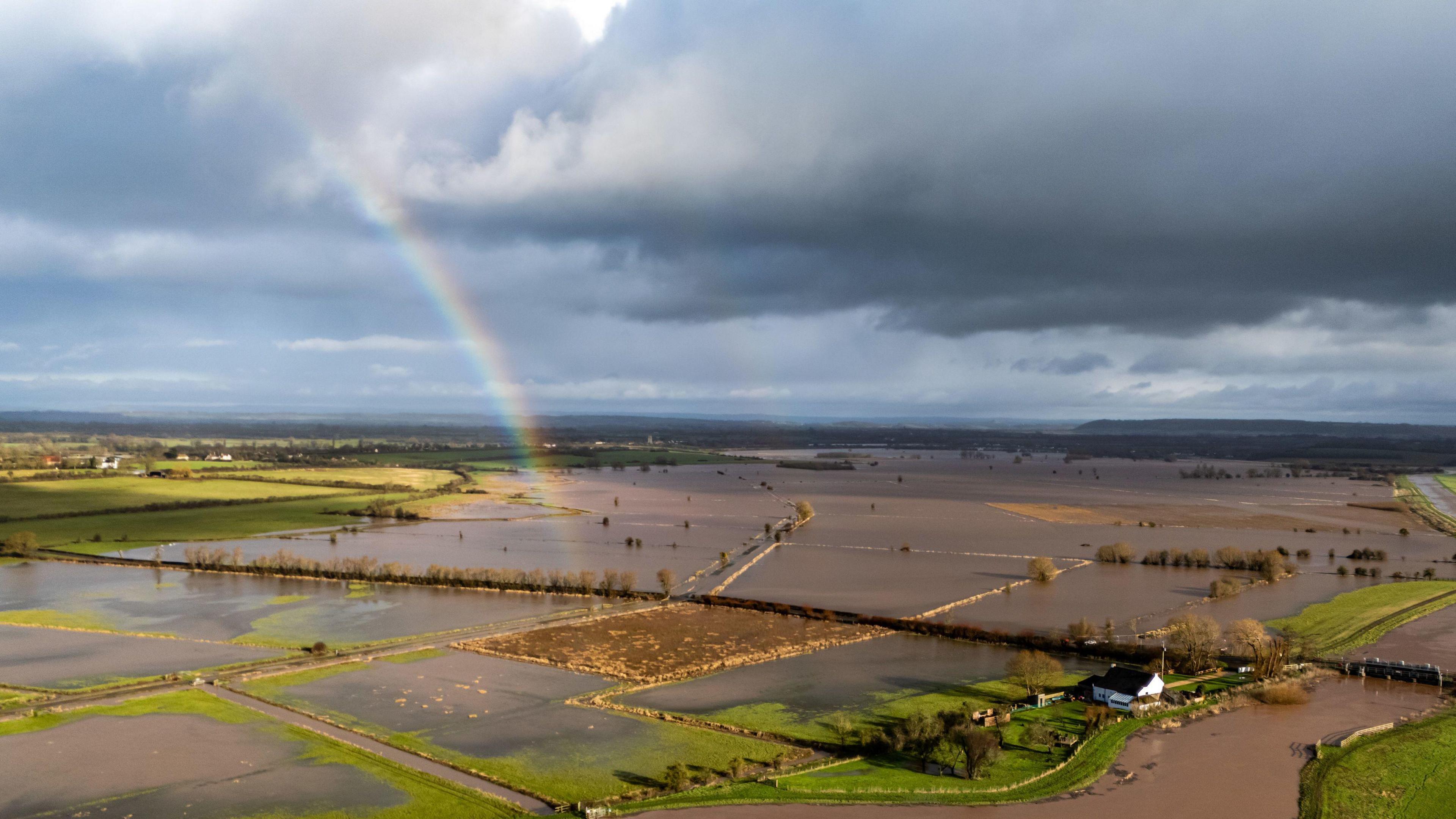 A rainbow is seen over flooded fields. The fields are seen from above.