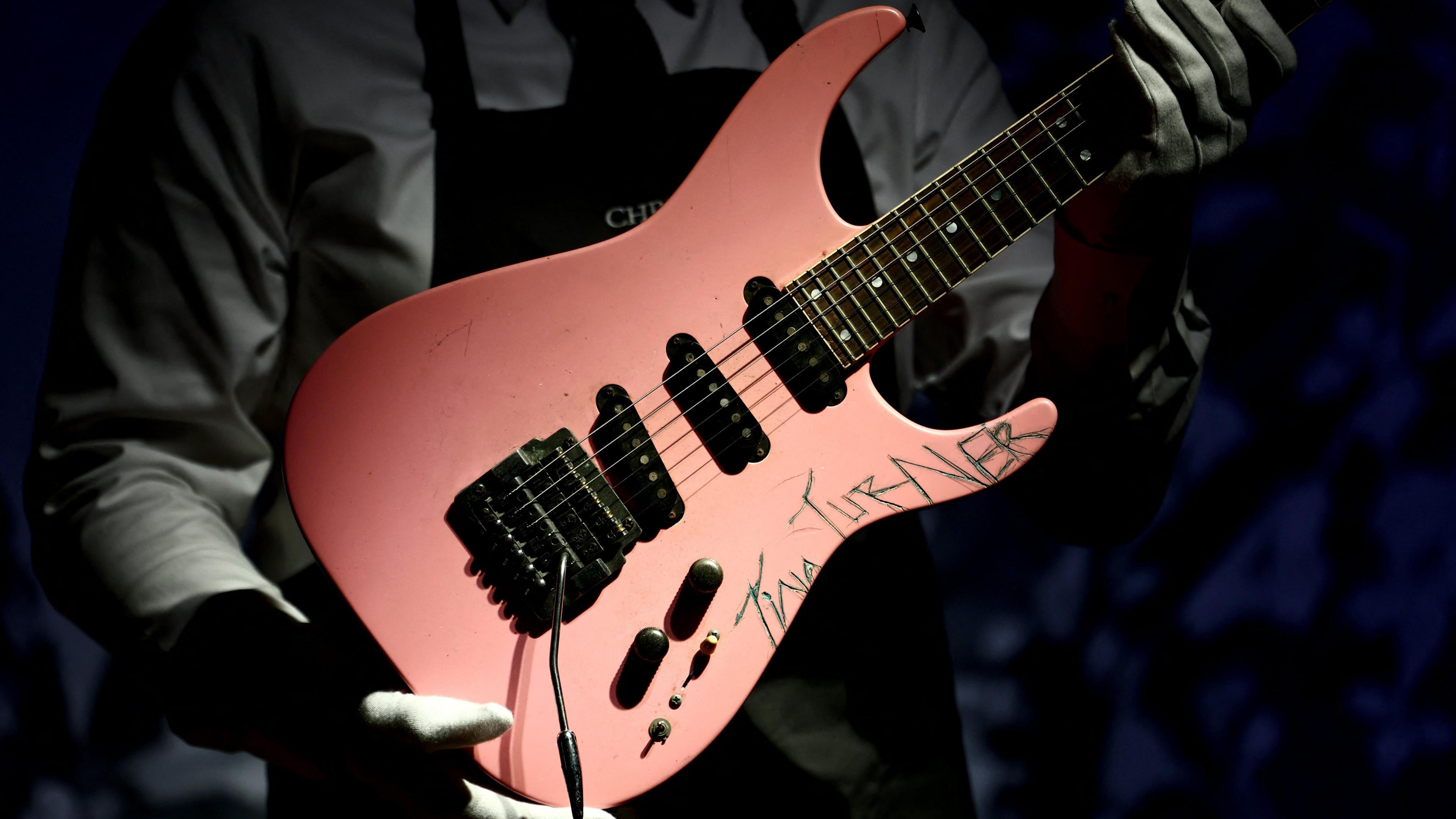 A pink guitar with "TINA TURNER" etched into the body.