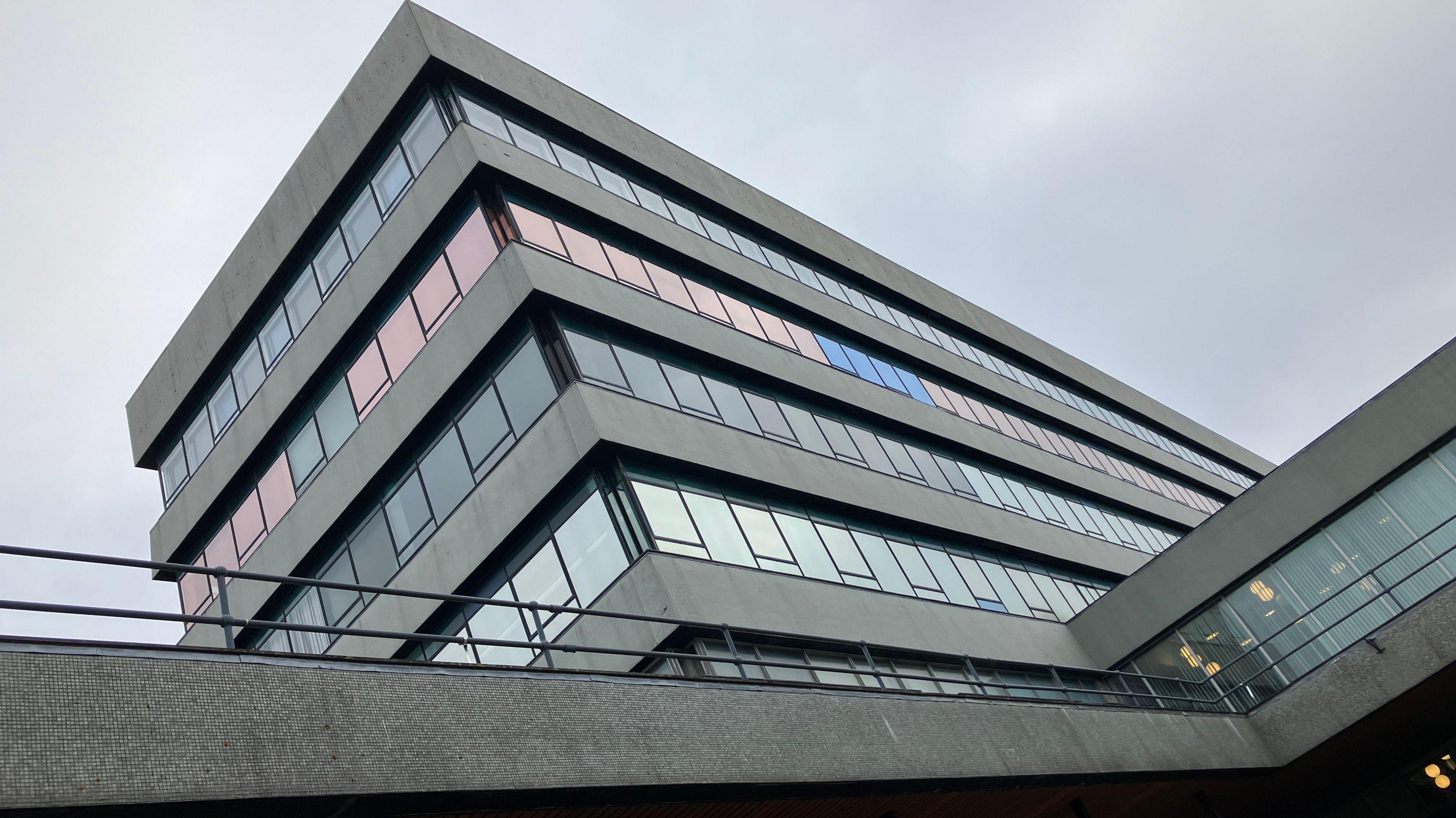 A flat roofed council building made of grey concrete and glass