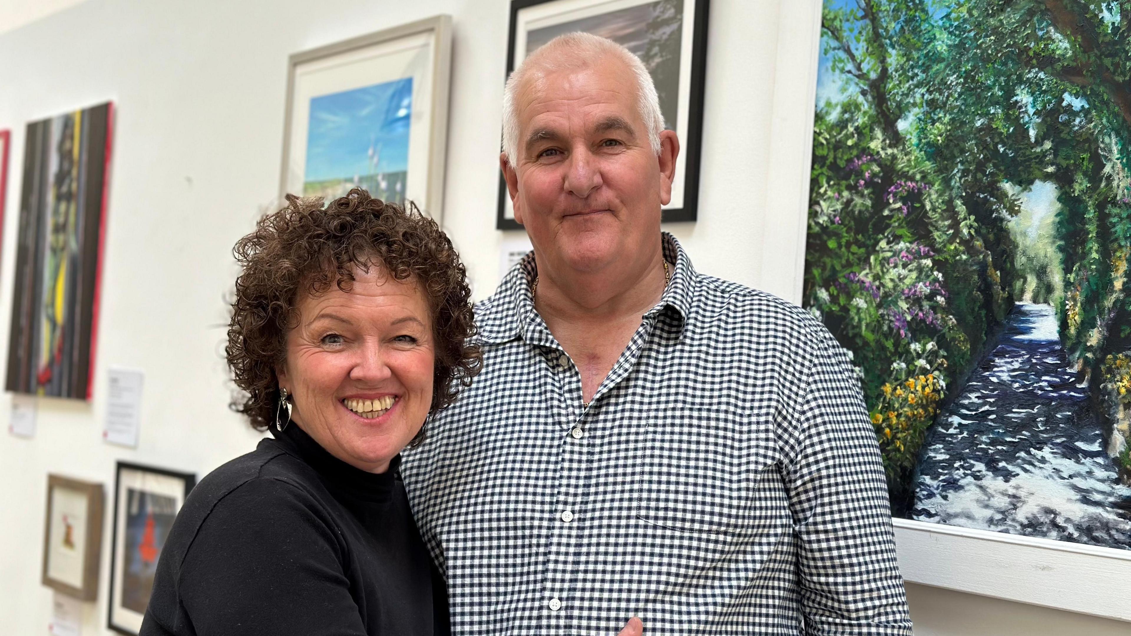 Woman, Jaki hugging fiancé Mark in front of art work