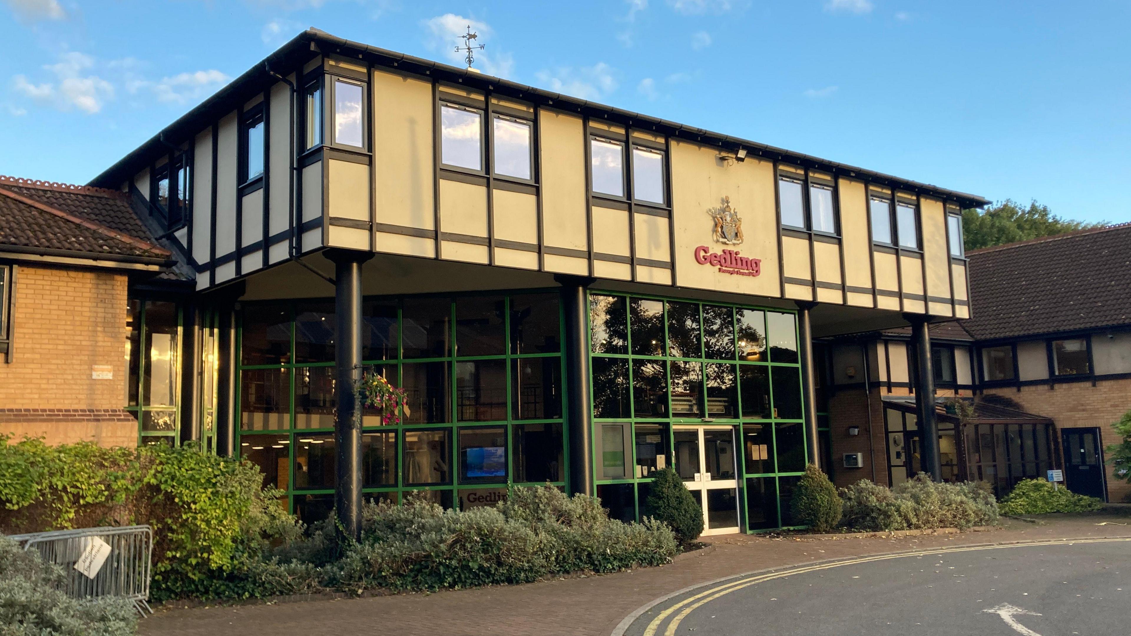 Gedling Borough Council's headquarters, with green-framed glass on the ground floor and beige cladding on the first floor. The council's red logo is seen in the middle of the first floor.