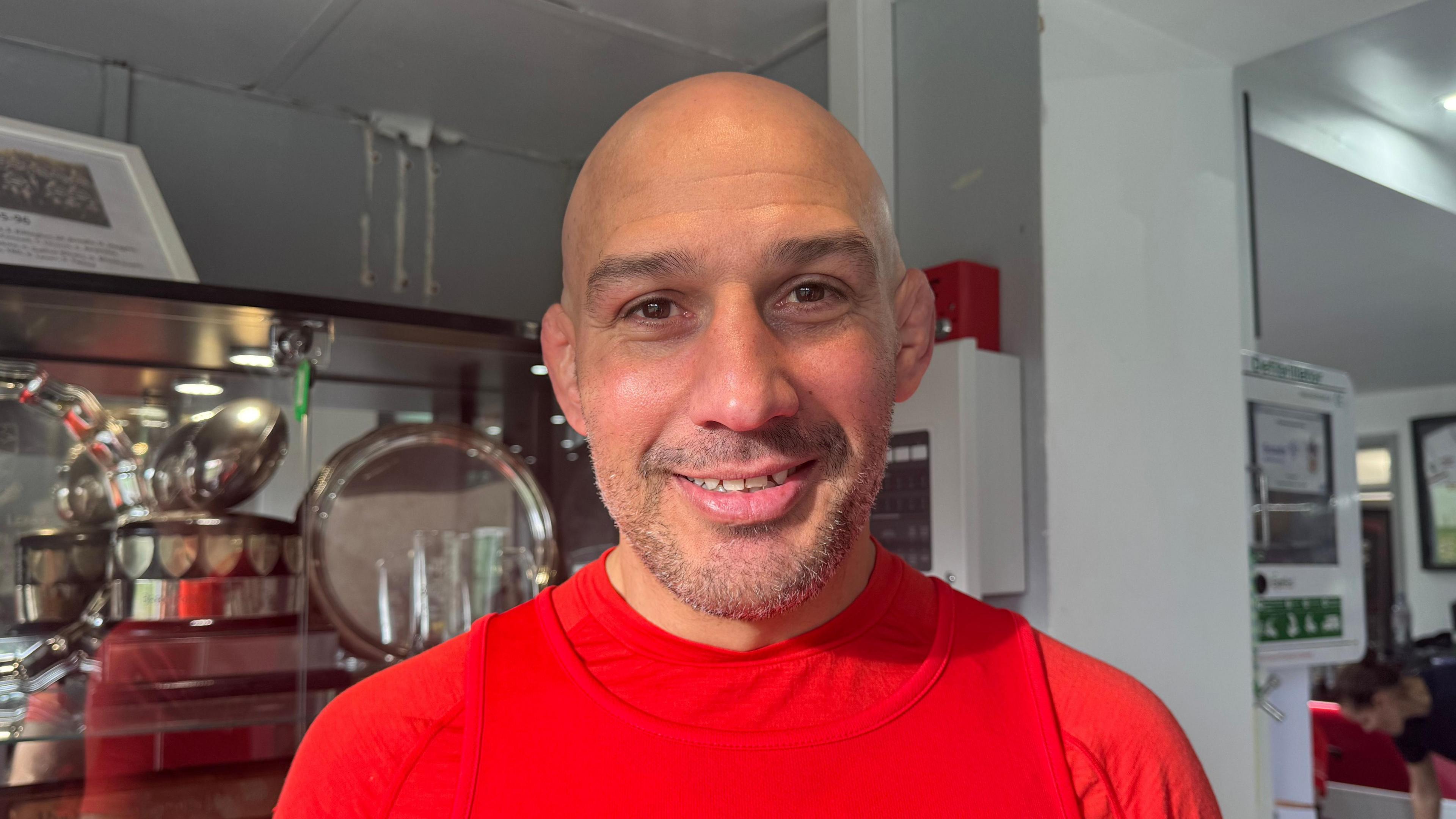 Andy Long wearing a red top smiling at camera. 