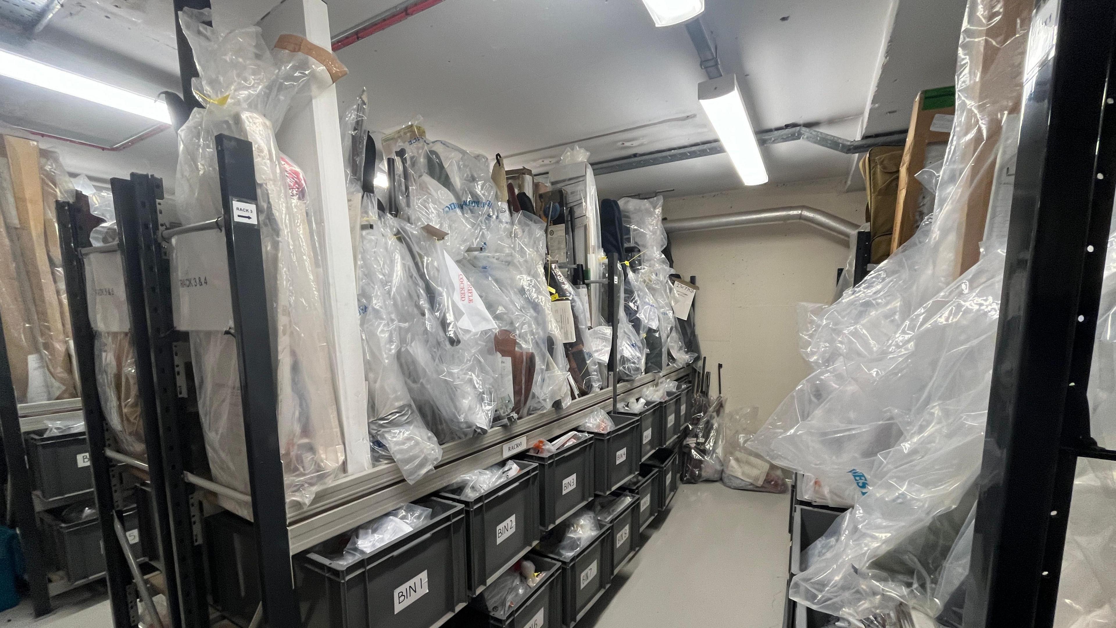 A picture of the police armoury, with guns covered in plastic lining the racks