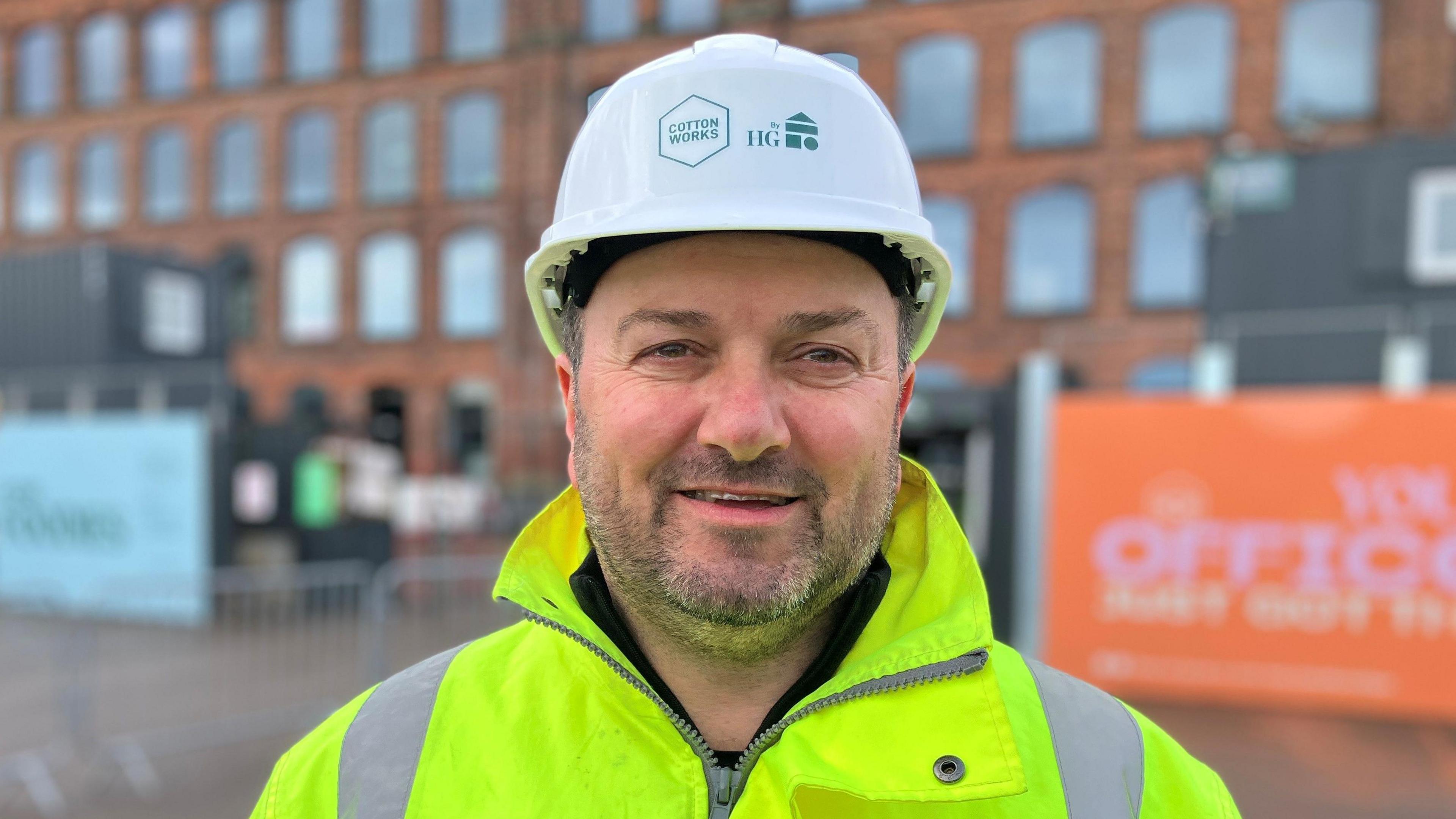 Heaton Group Managing Director John Heaton poses for a photograph while wearing a bright yellow hi-viz jacket and white hard hat.