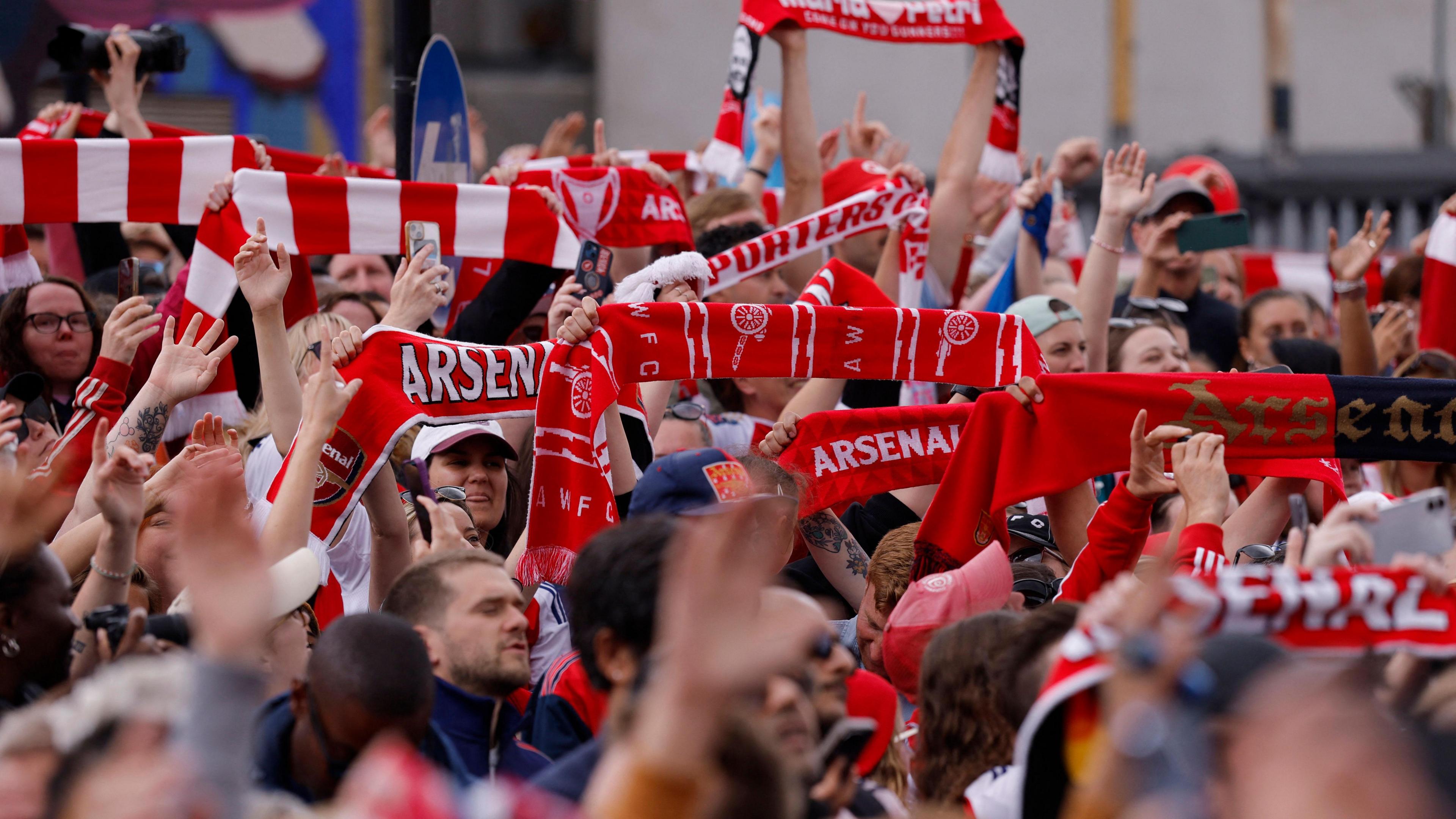 Fans in the crowd smiling and waving scarves