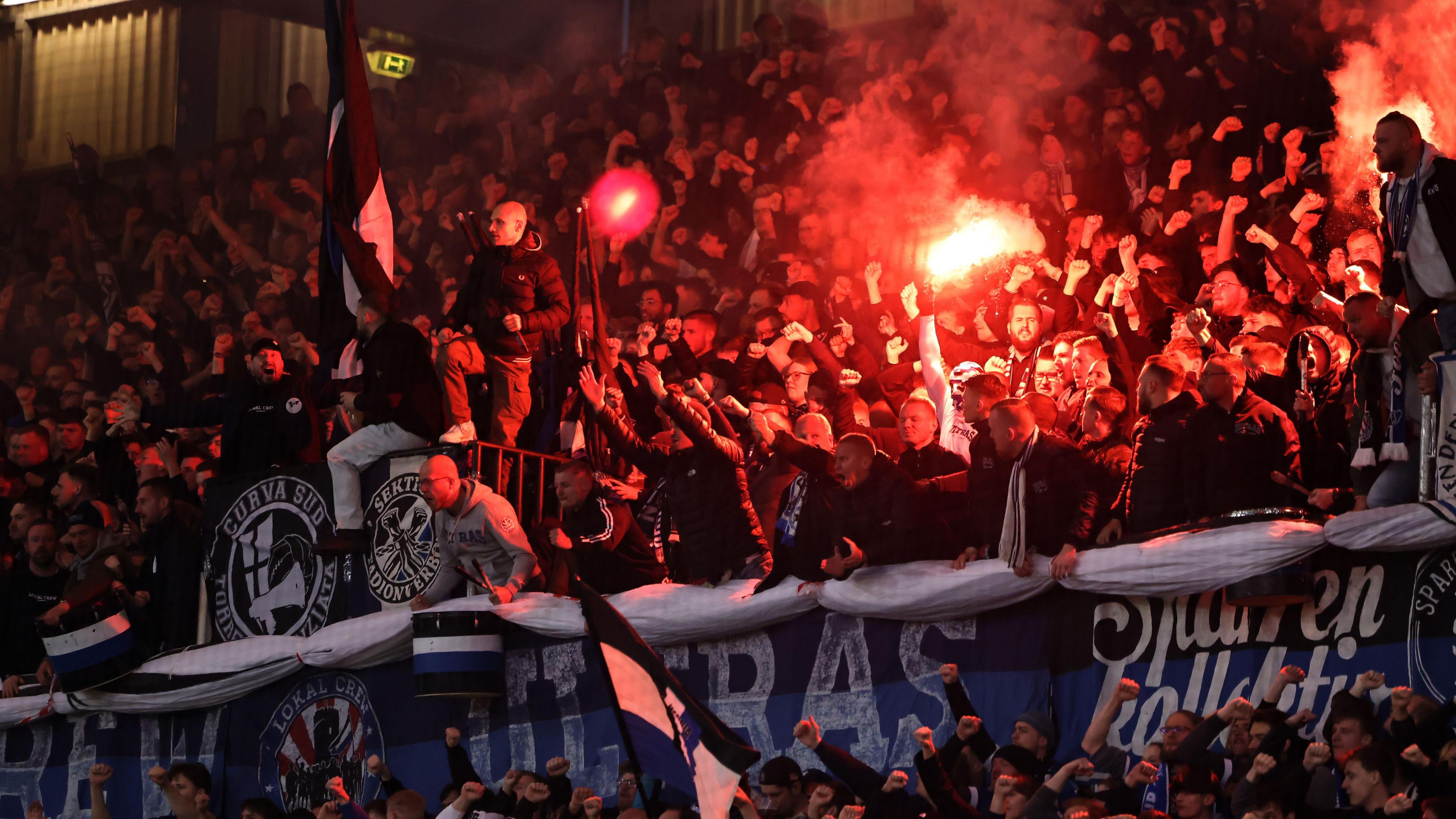 Arminia fans light a flare and chant inside the Schuco Arena