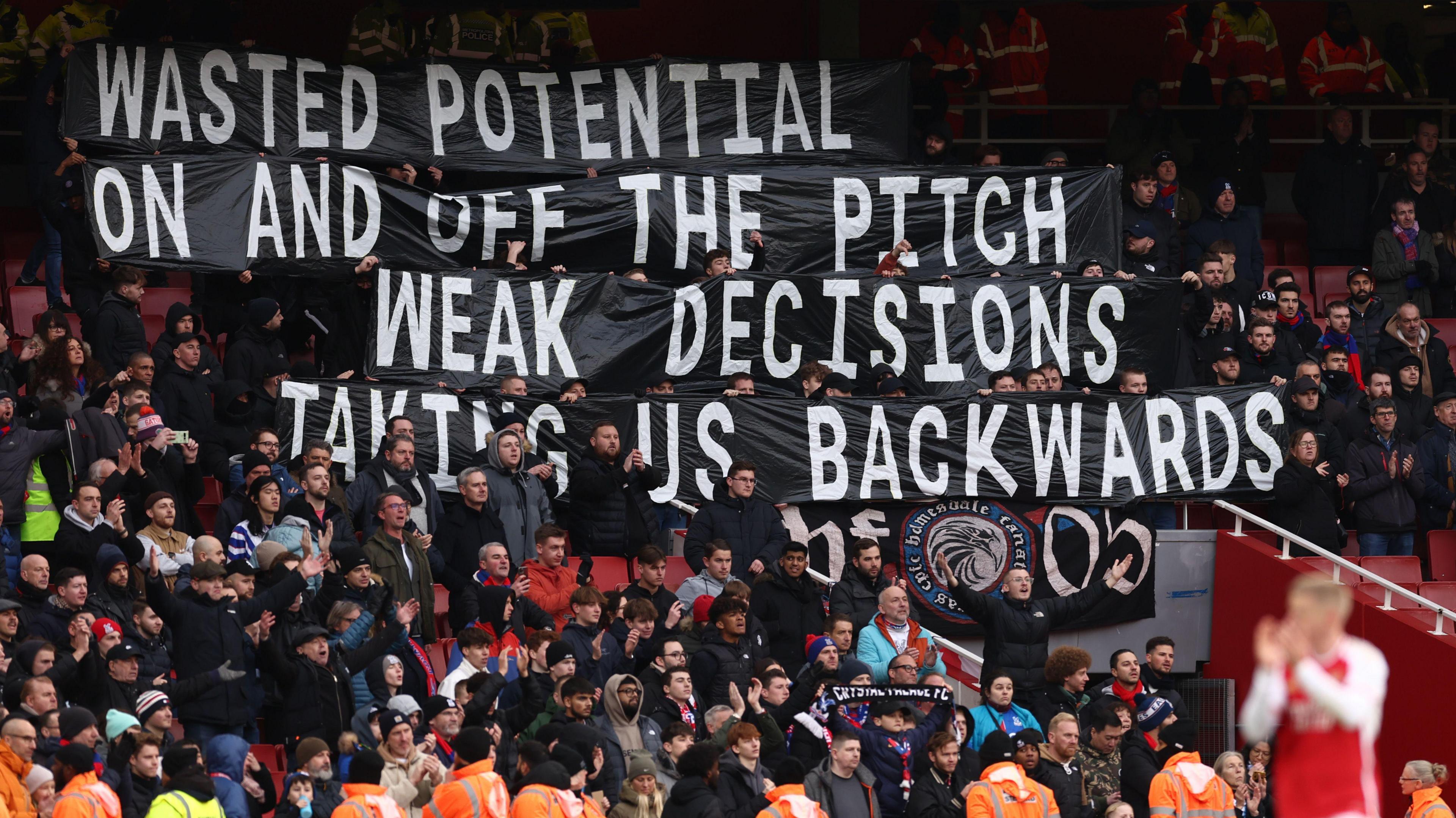 Crystal Palace fans hold up banners protesting against the club