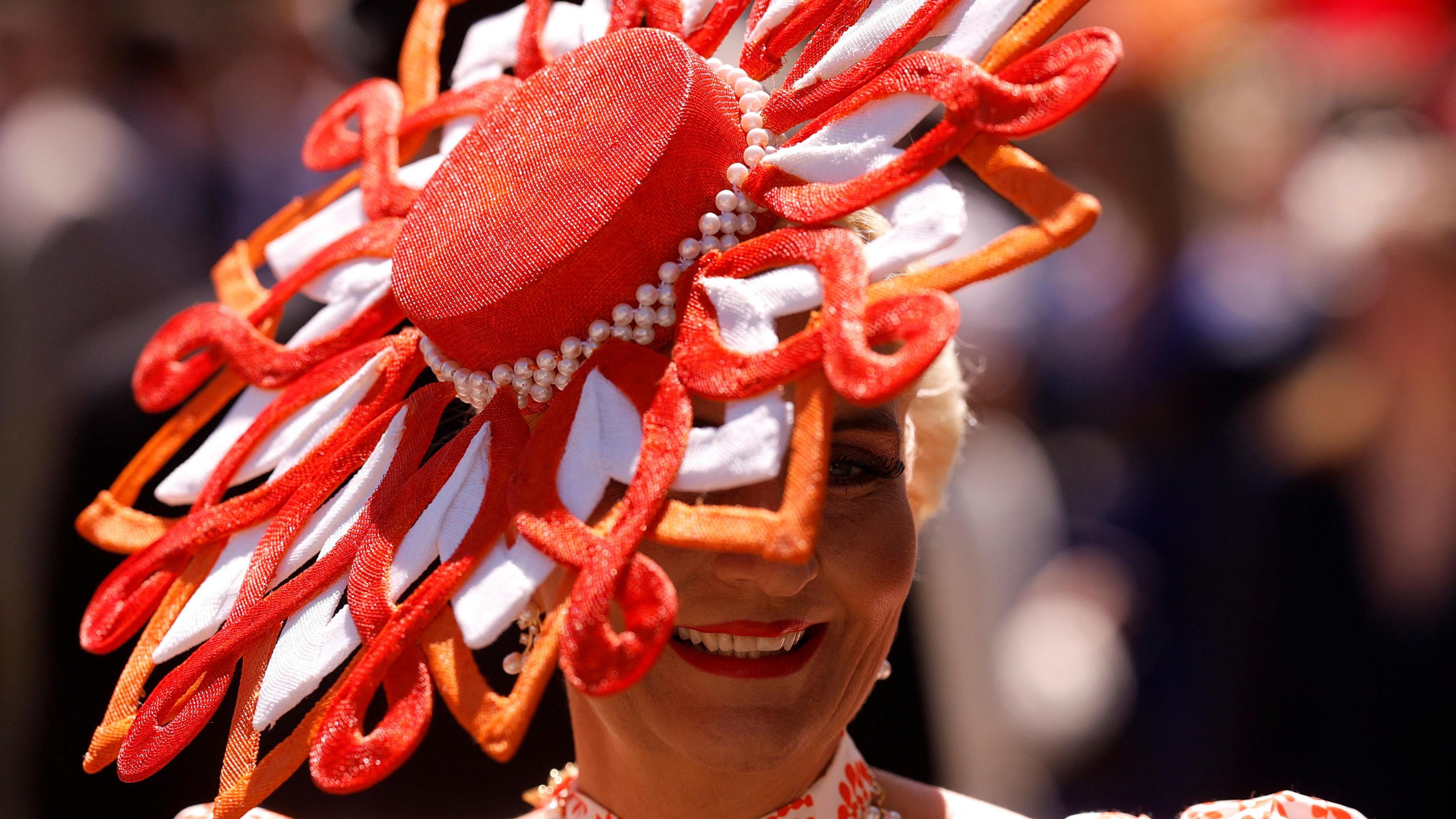 Woman wears an orange and white decorative hat