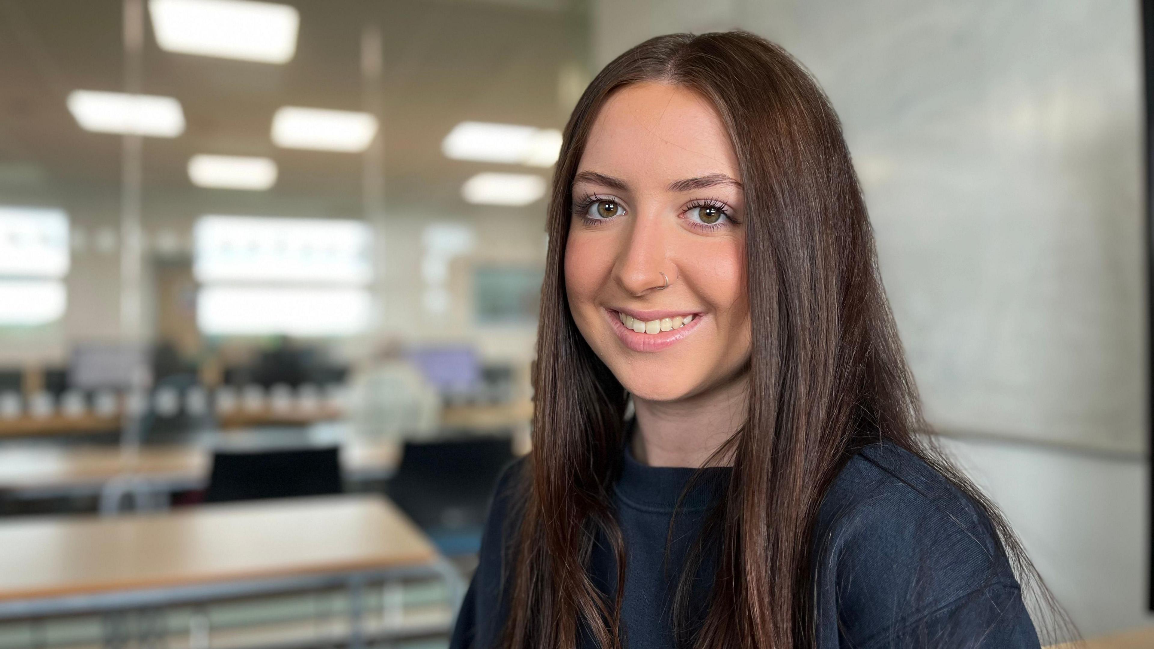 Maya Nann at Lakes College. She has long, dark hair and wears a dark blue jumper