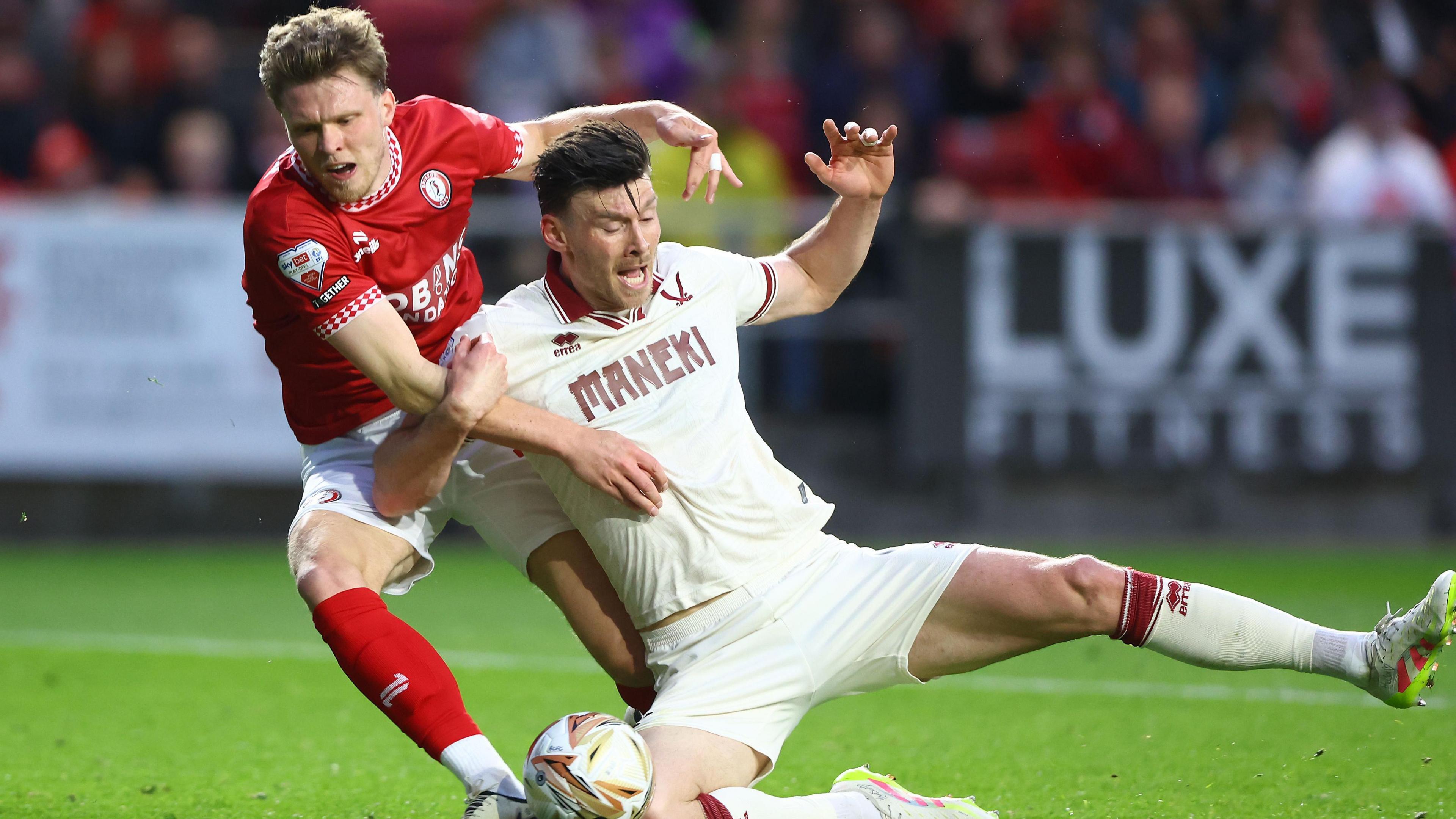 Rob Dickie in his red shirt and white shorts pulling Kieffer Moore down to the ground
