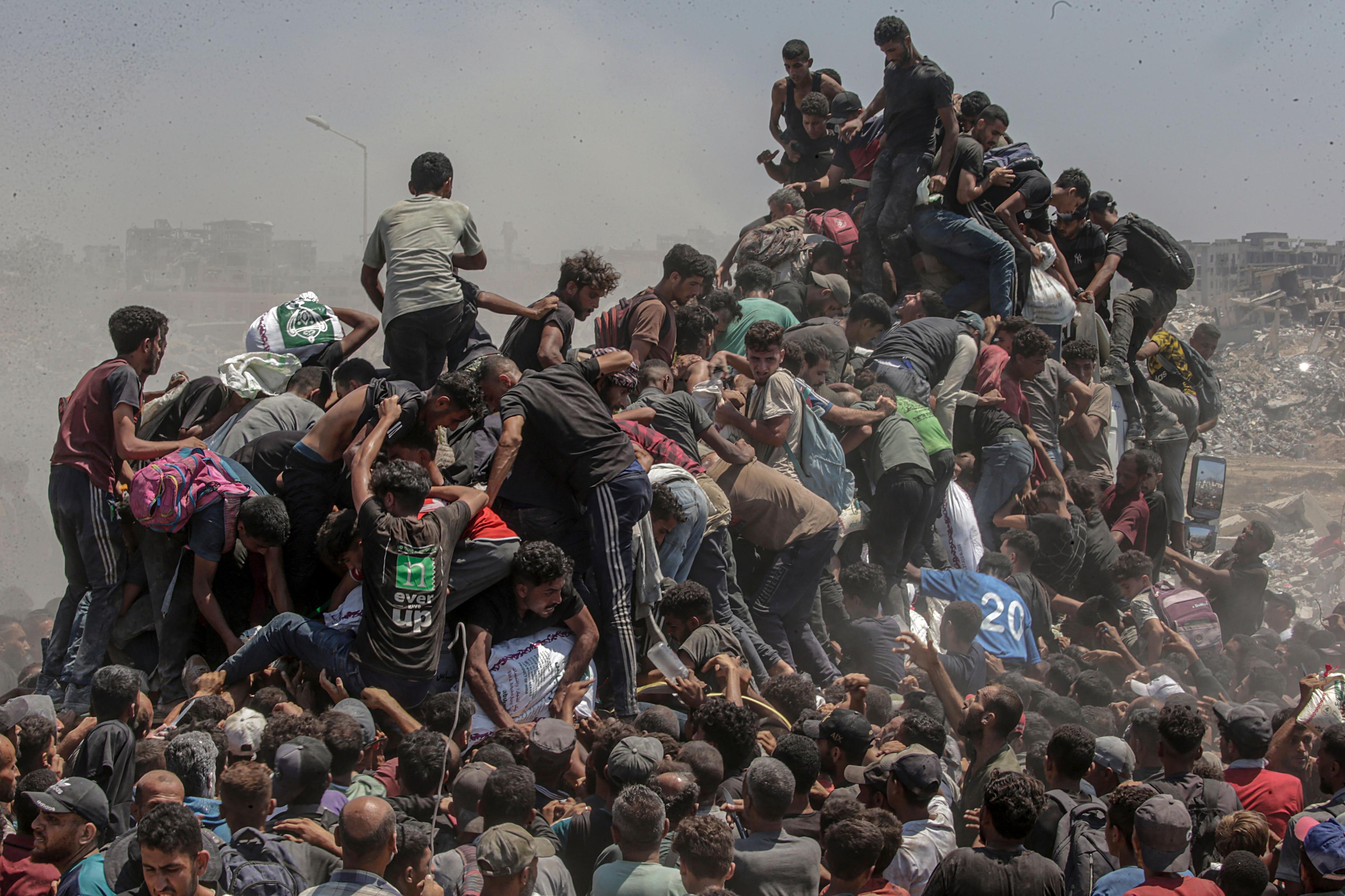 Palestinians try to grab bags of flour from an aid truck near Zikim, northern Gaza Strip on 27 July