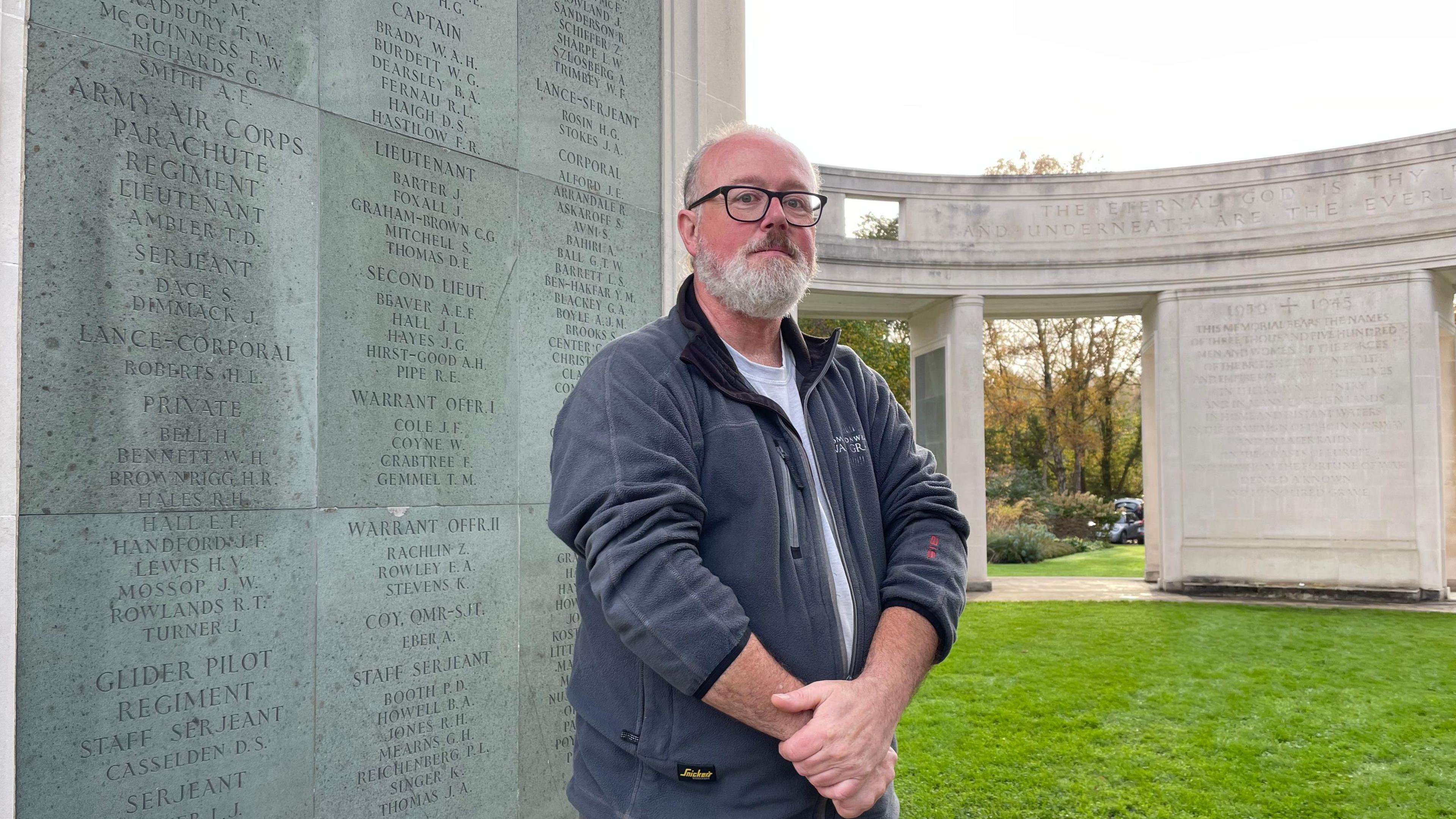 Senior gardener Bob Thomson wearing gardening clothes and standing in front of graves at Brookwood Military Cemetery.