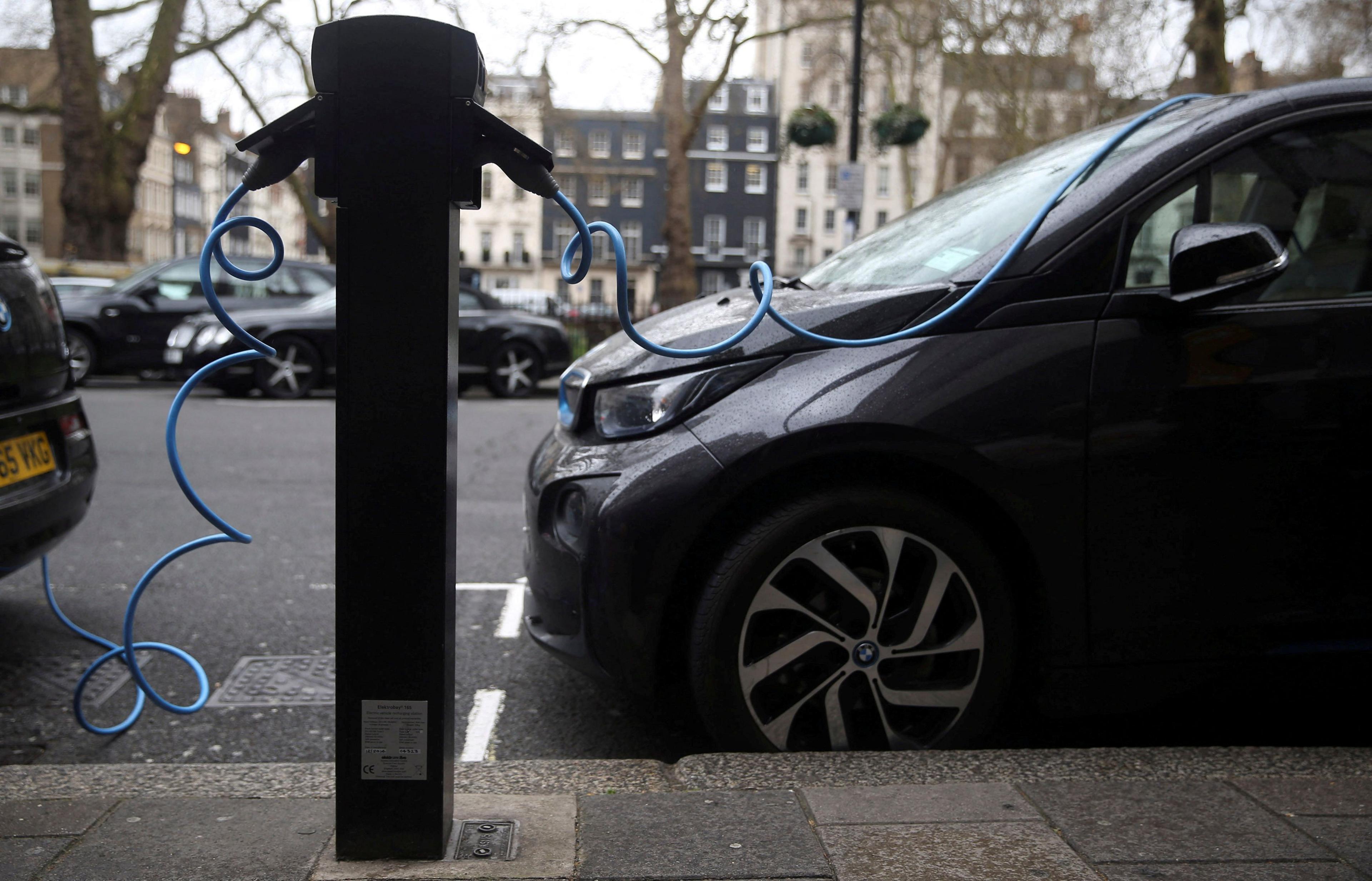 Two black electric cars are plugged into a charging point