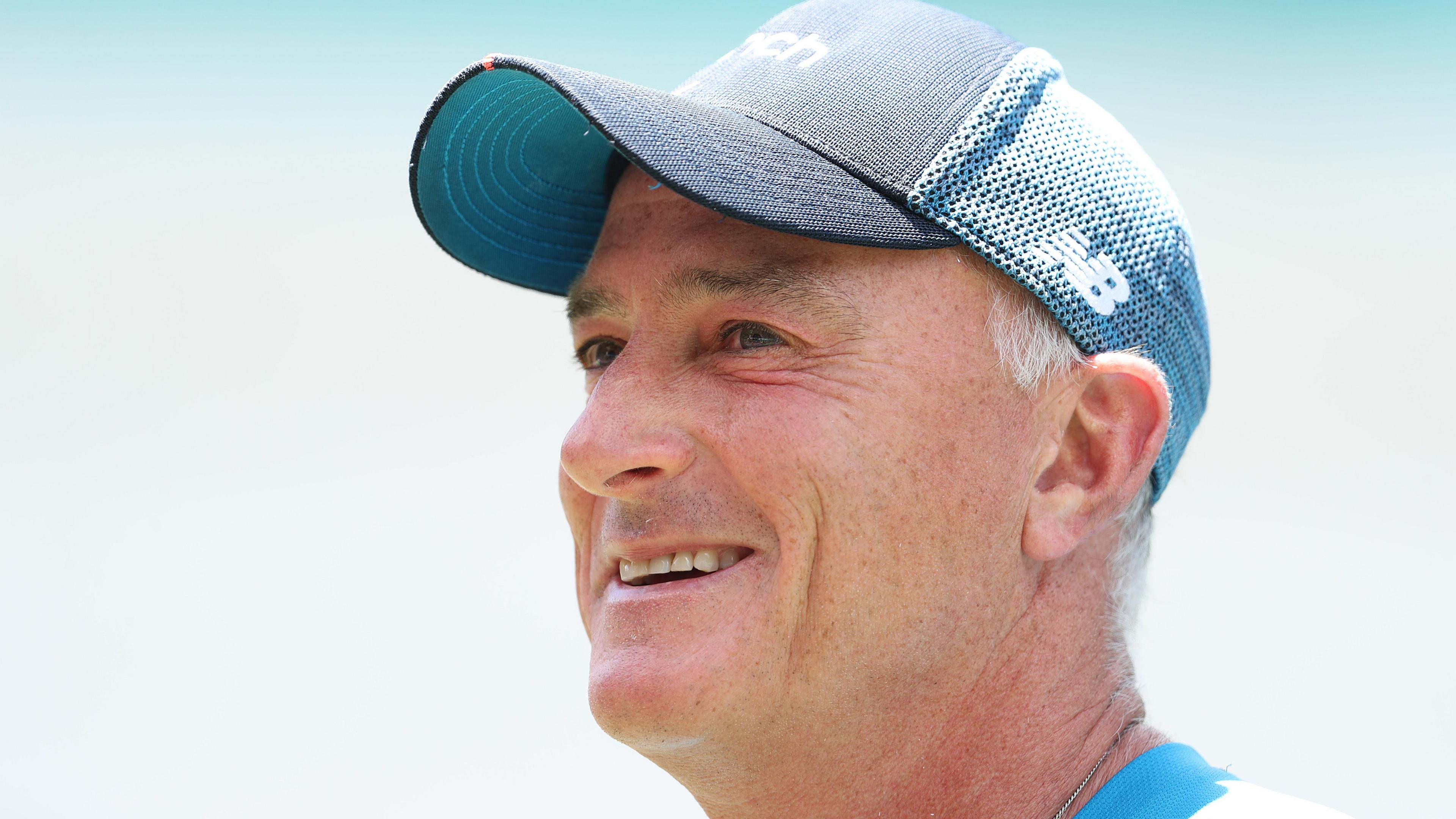 England assistant coach Graham Thorpe talks to media during an England nets session at Sydney Cricket Ground on January 04, 2022 in Sydney, Australia. He is smiling and wearing a dark & light blue cap. He is looking up and to the left of the screen