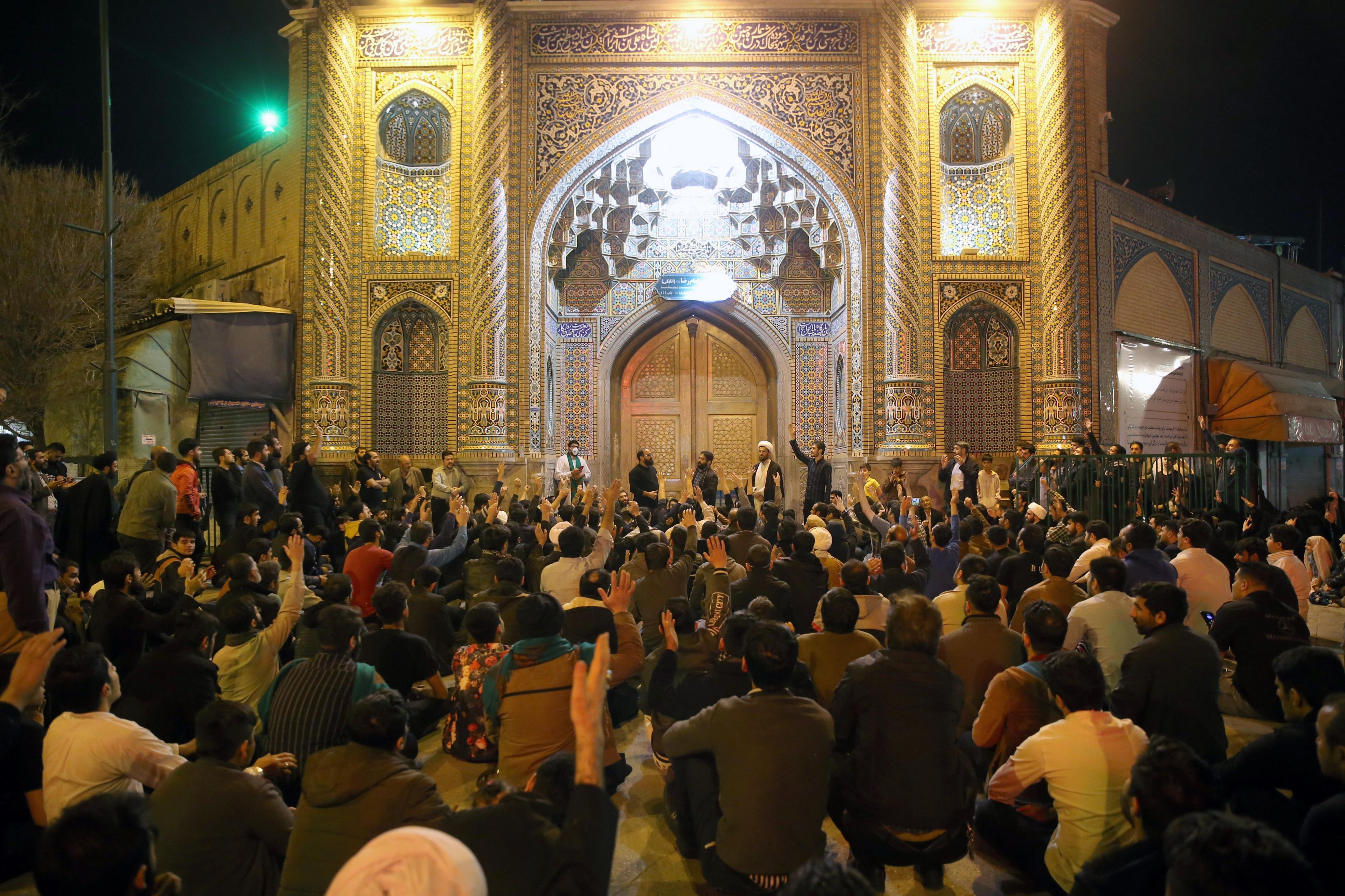 People gather outside the closed doors of the Fatima shrine in Iran's holy city of Qom