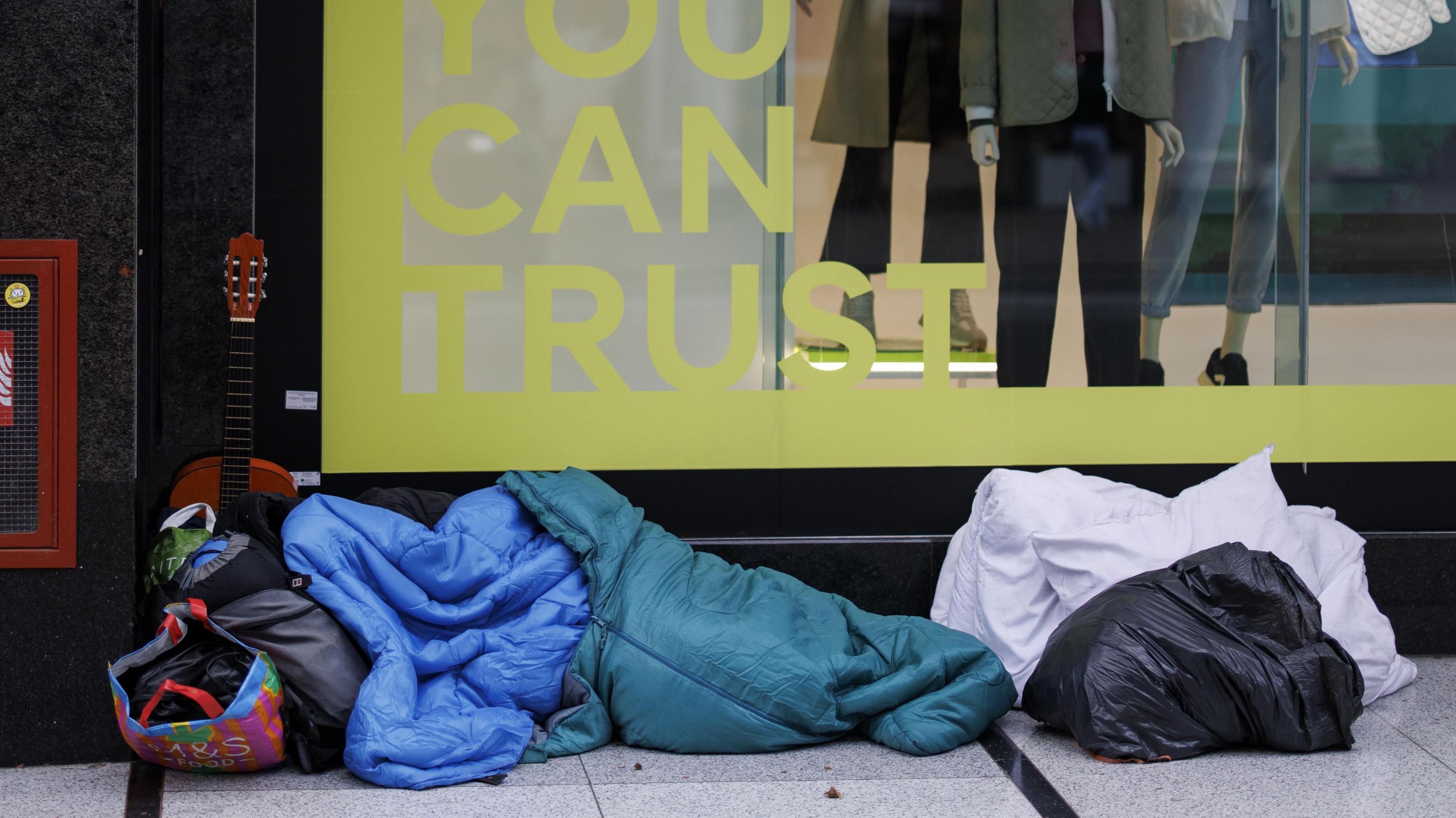 A homeless person sleeps in a sleeping bag on Oxford Street in London.