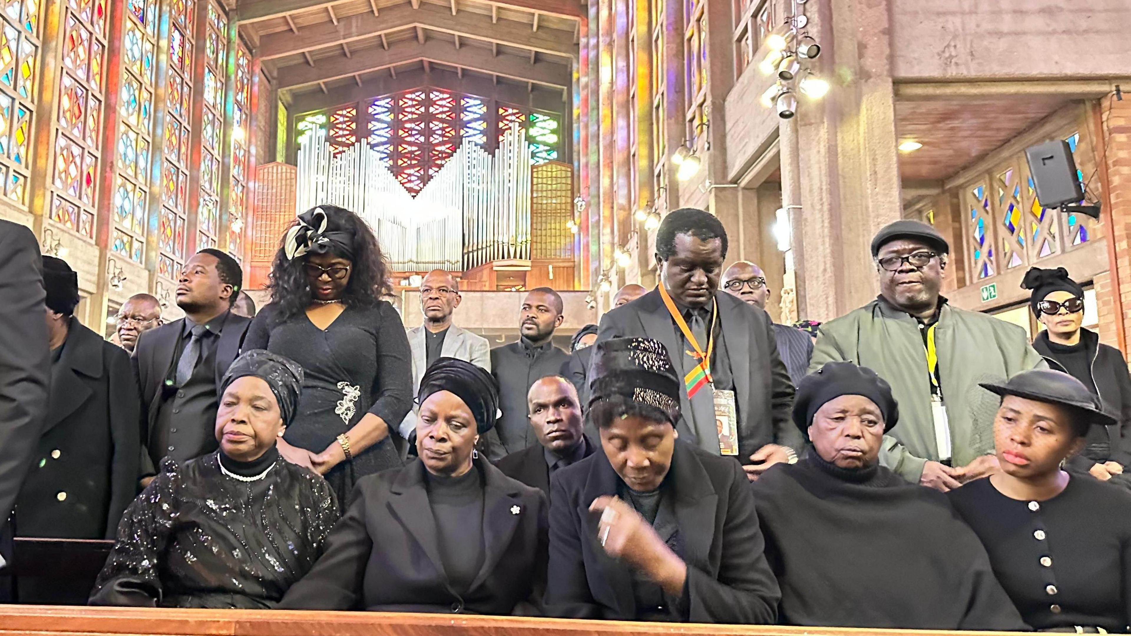 Mourners dressed in black sit in a pew at a mass held for the former Zambian statesman in Johannesburg
