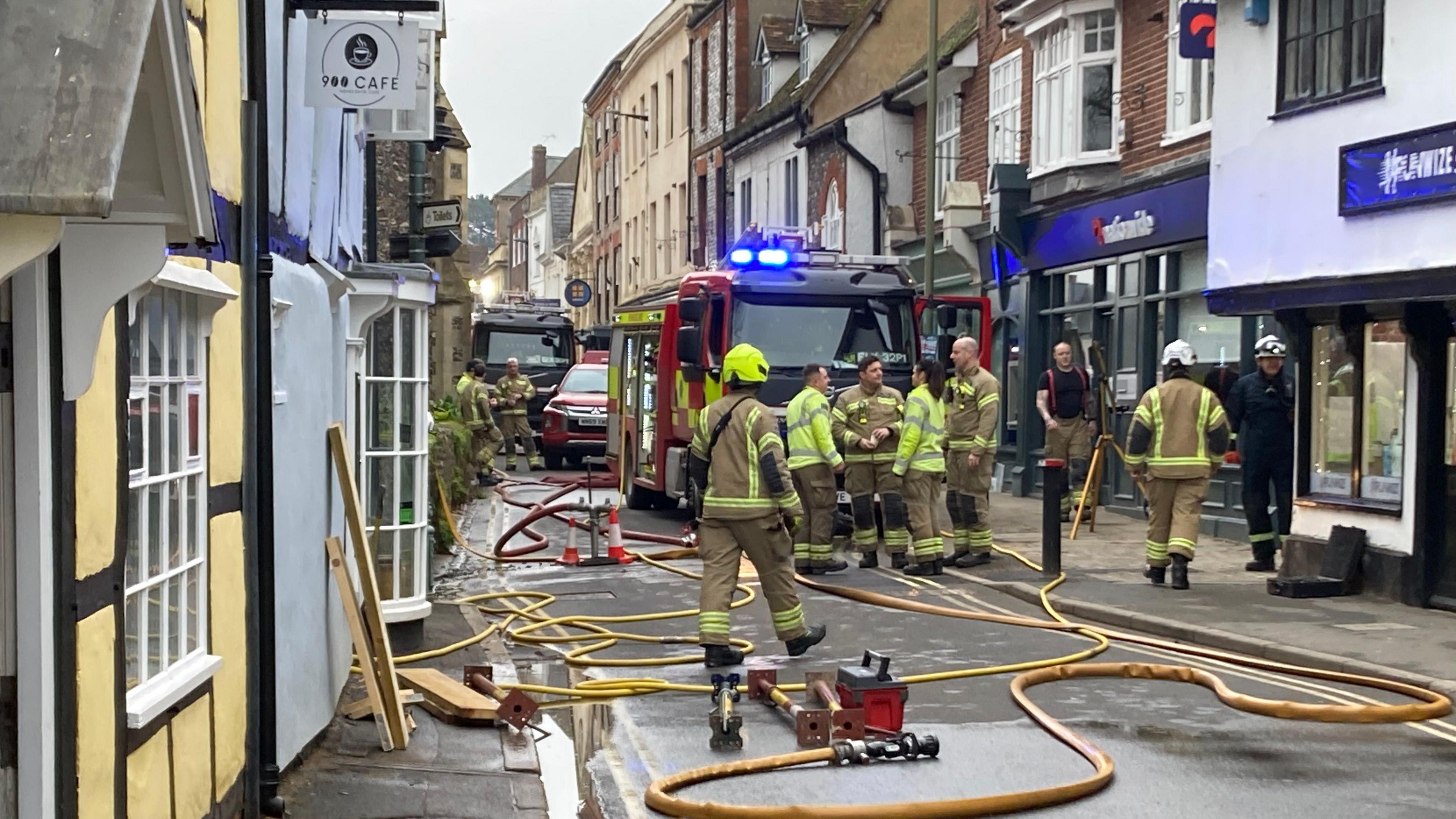 Firefighters gathered in front of a fire engine in Wallingford's St Mary's Street, with hoses in front of the building.