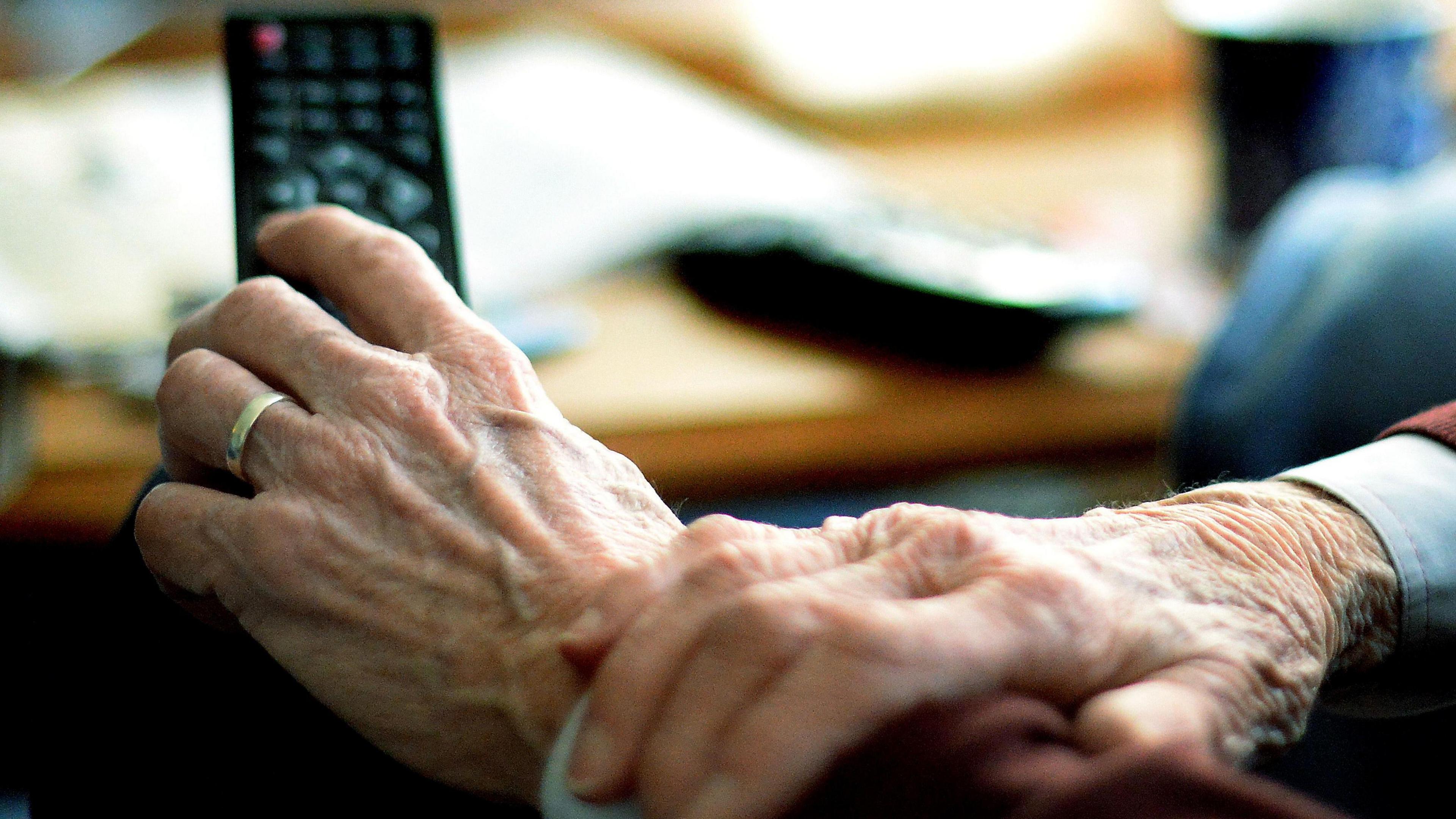 Old person holding TV remote control