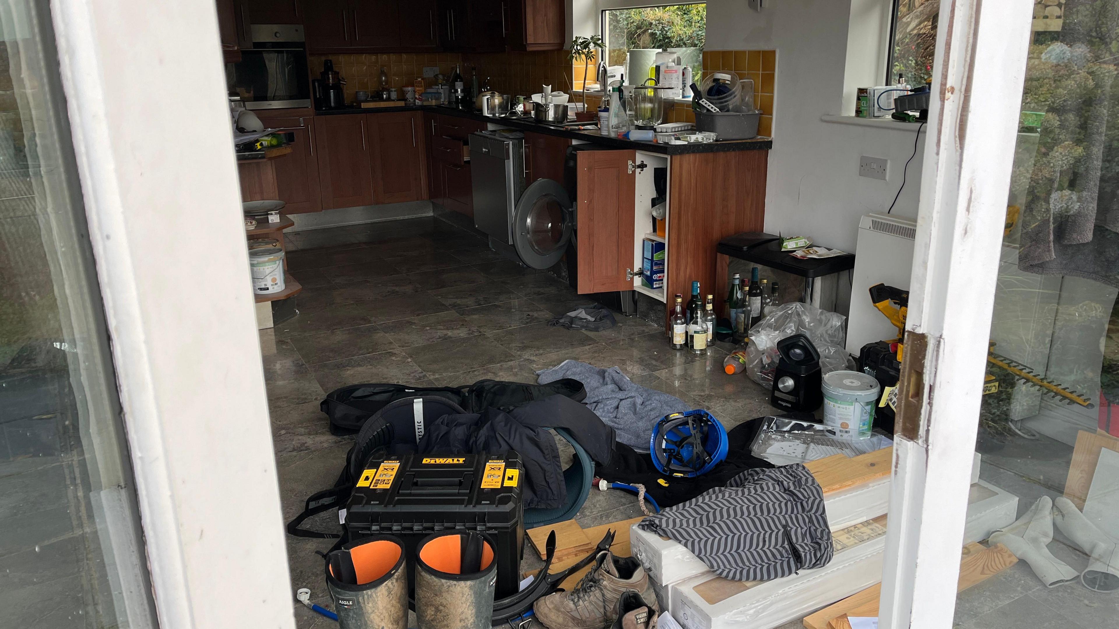 Kitchen with cupboard doors open and pans and crockery were spread over the kitchen sink and worktop