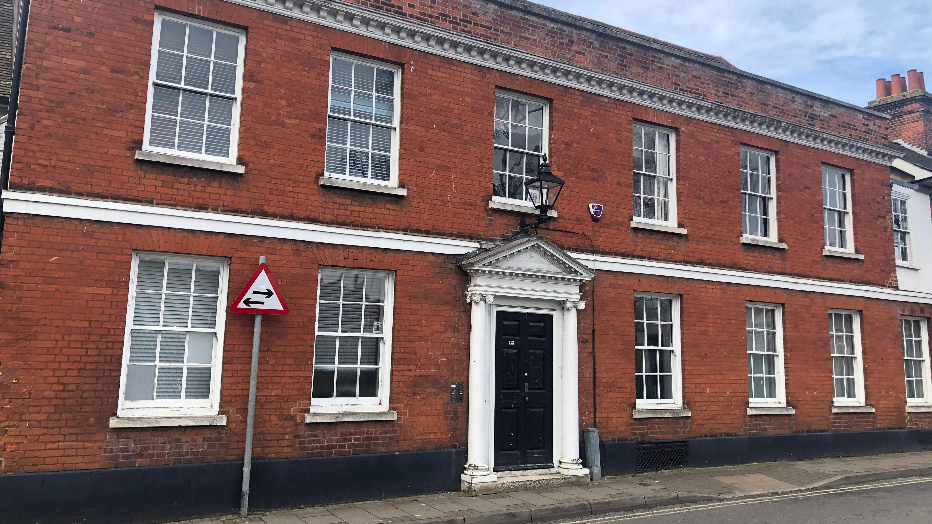 19 Tower Street in Ipswich - a two story brick building with a black front door with white columns either side