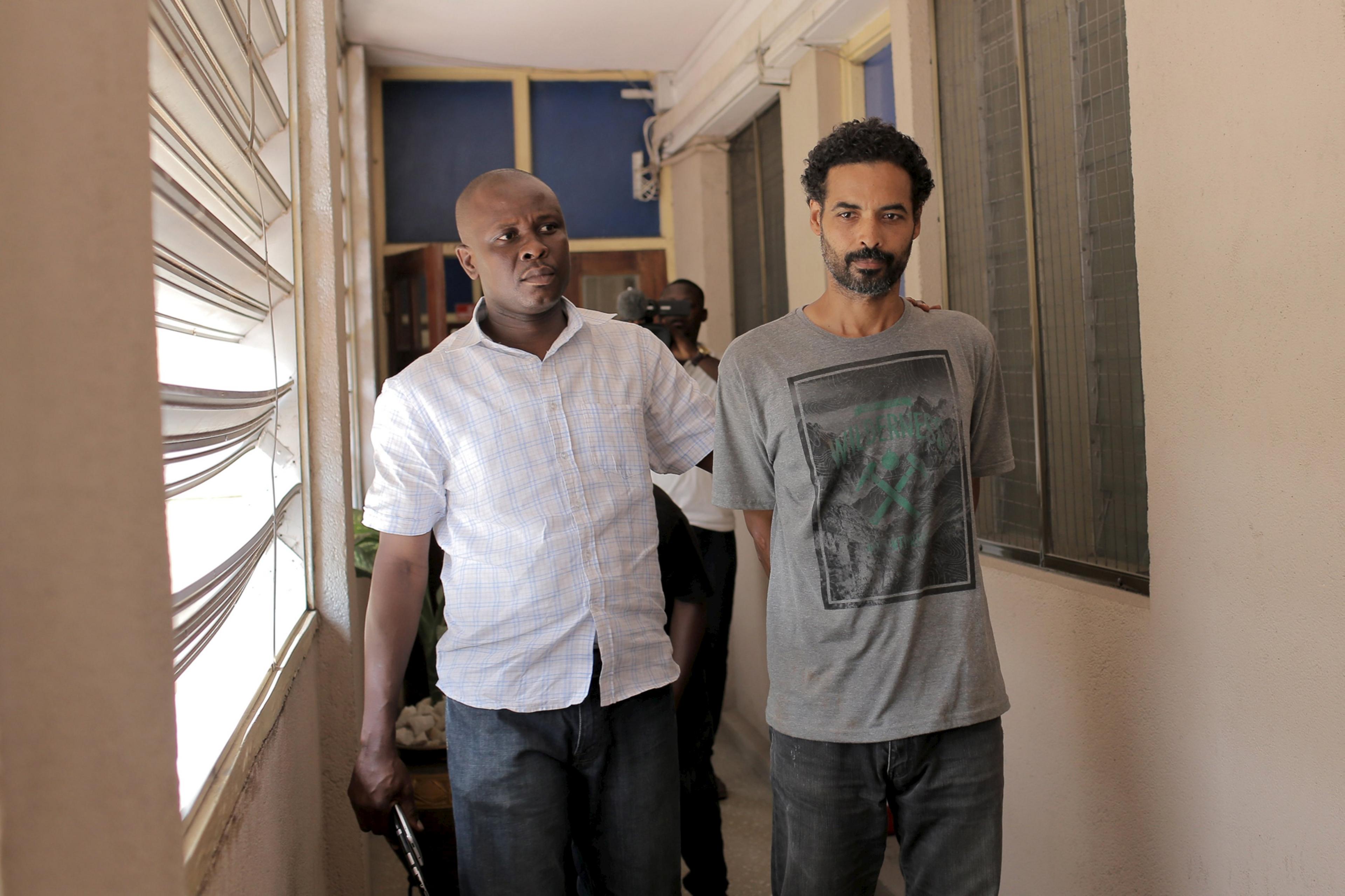 Police officer escorts Arthur Simpson-Kent (right) inside the Criminal Investigation Department headquarters in Accra, Ghana, on 10 January 2016