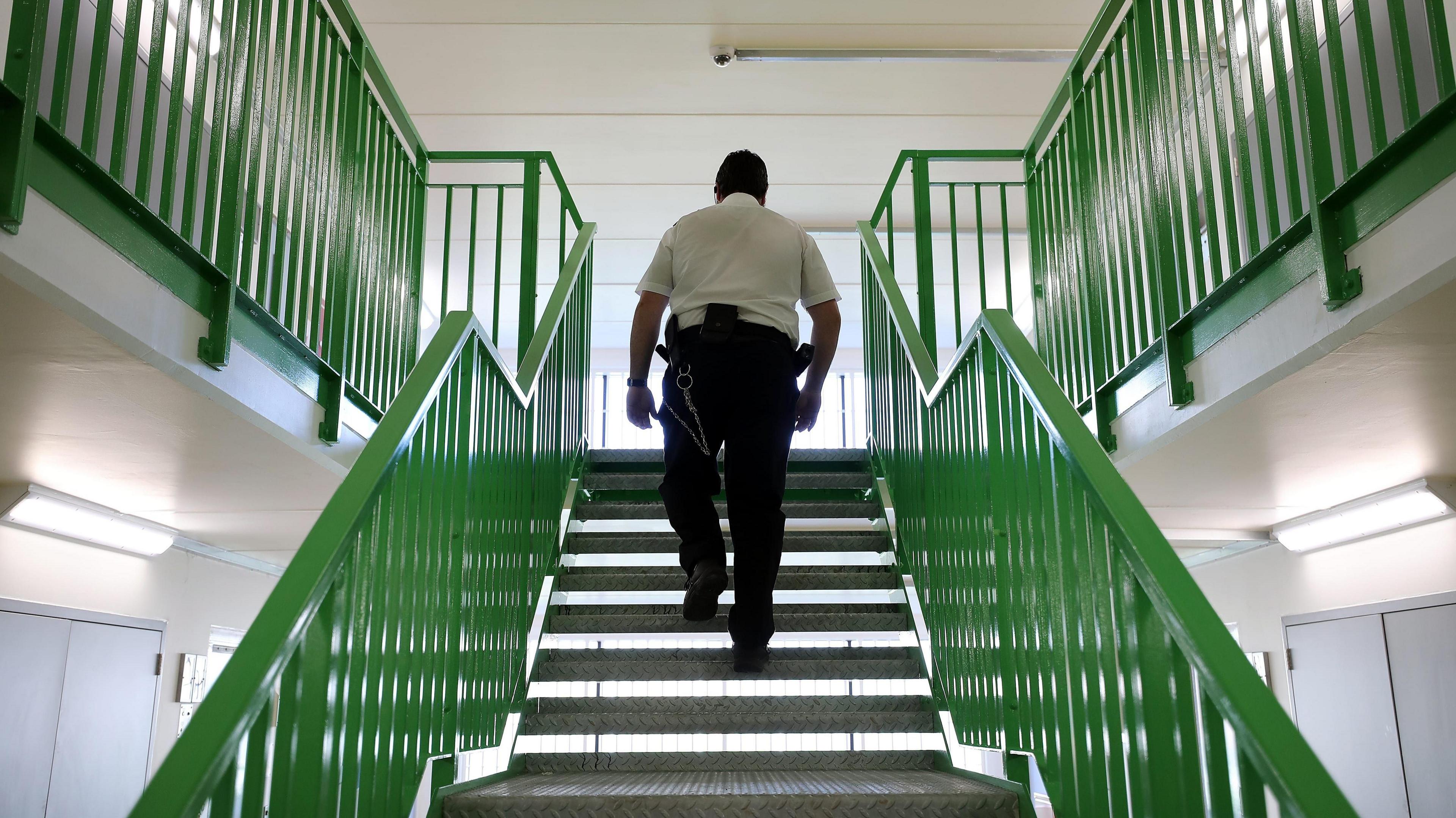 A prison guard walks through a cell area at HMP Berwyn