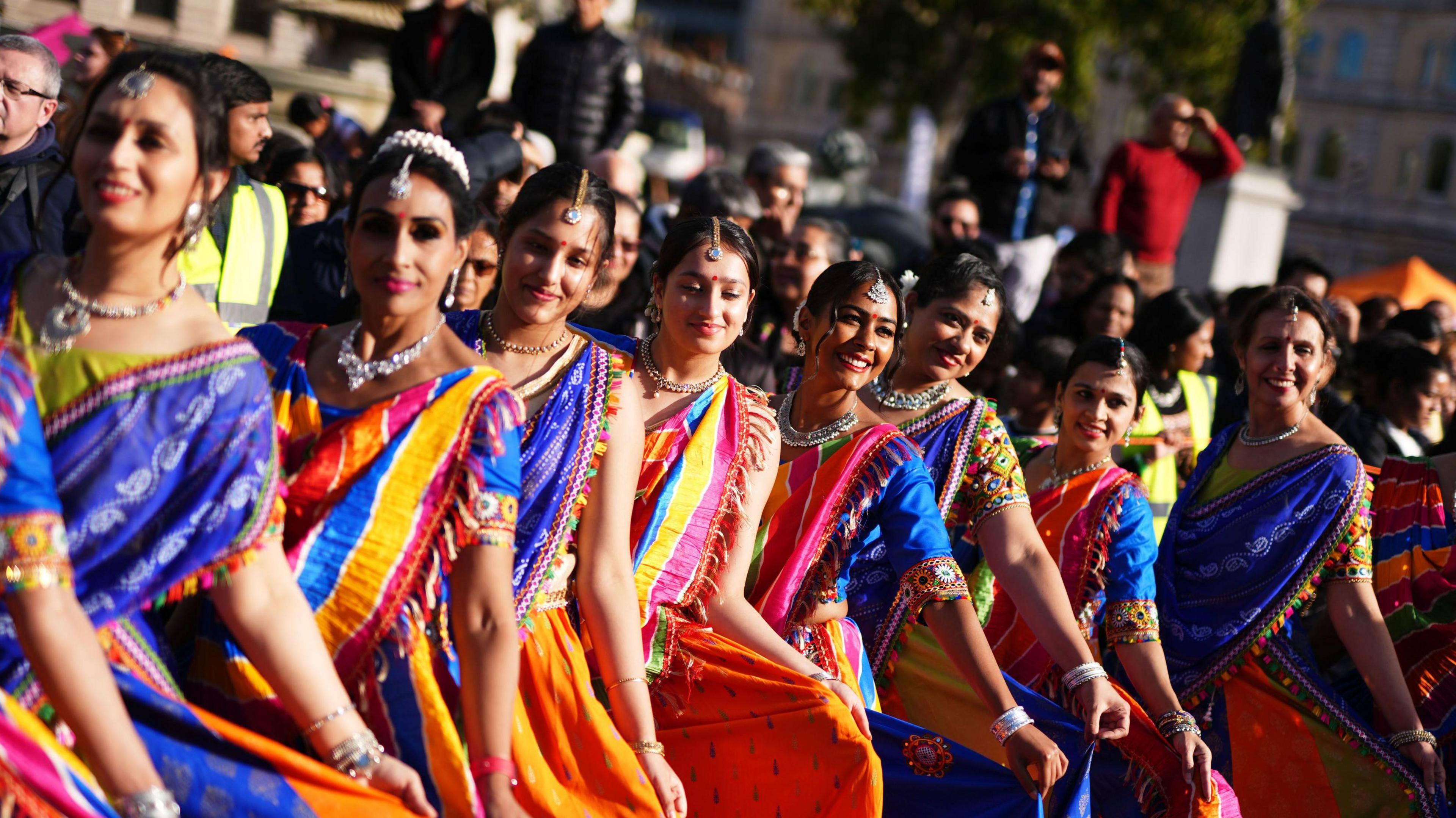 Dancers hold out their blue, pink and orange Saris in a line during the Diwali on the Square celebration