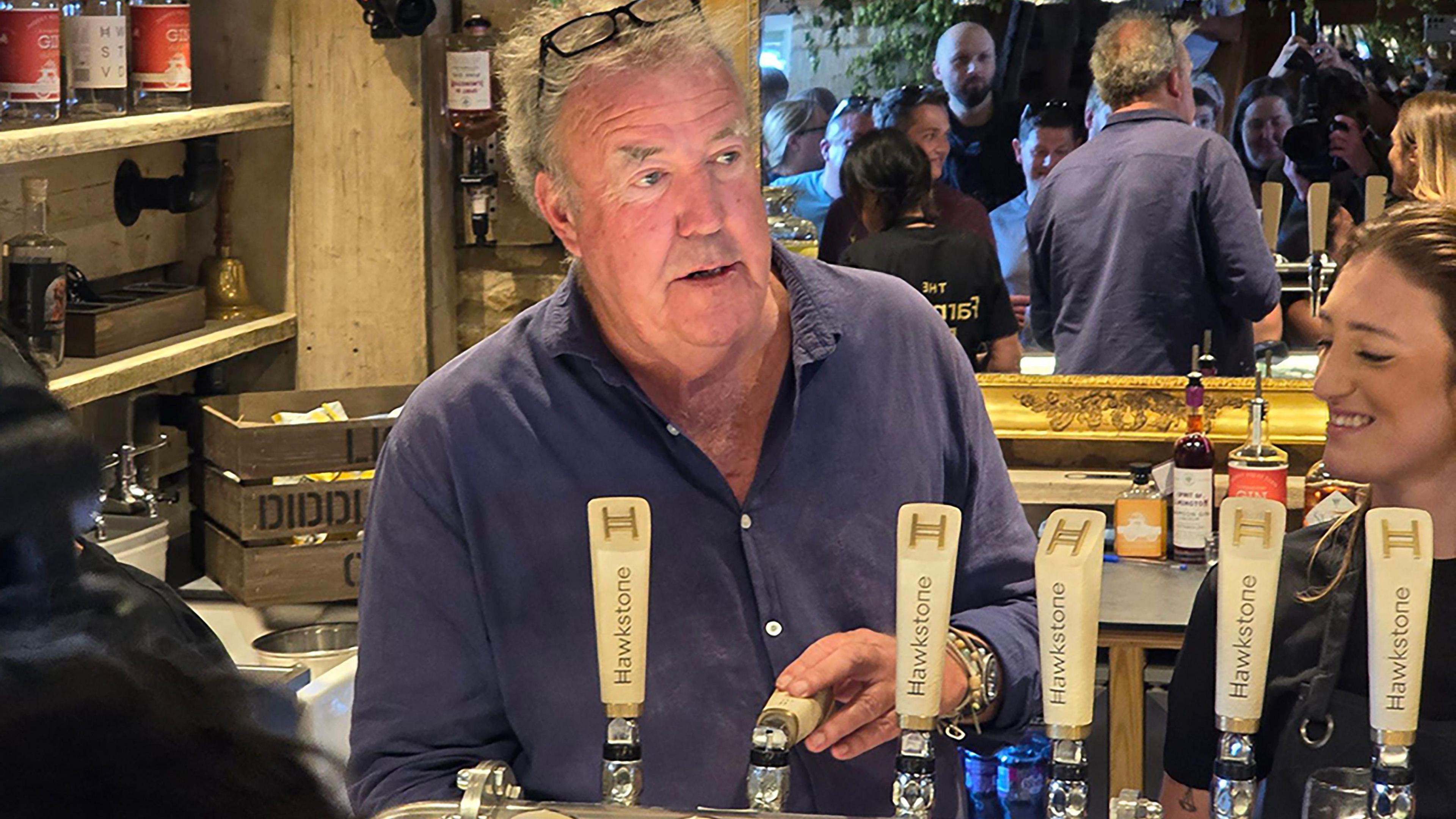 Jeremy Clarkson pulls a pint behind the bar of his pub.