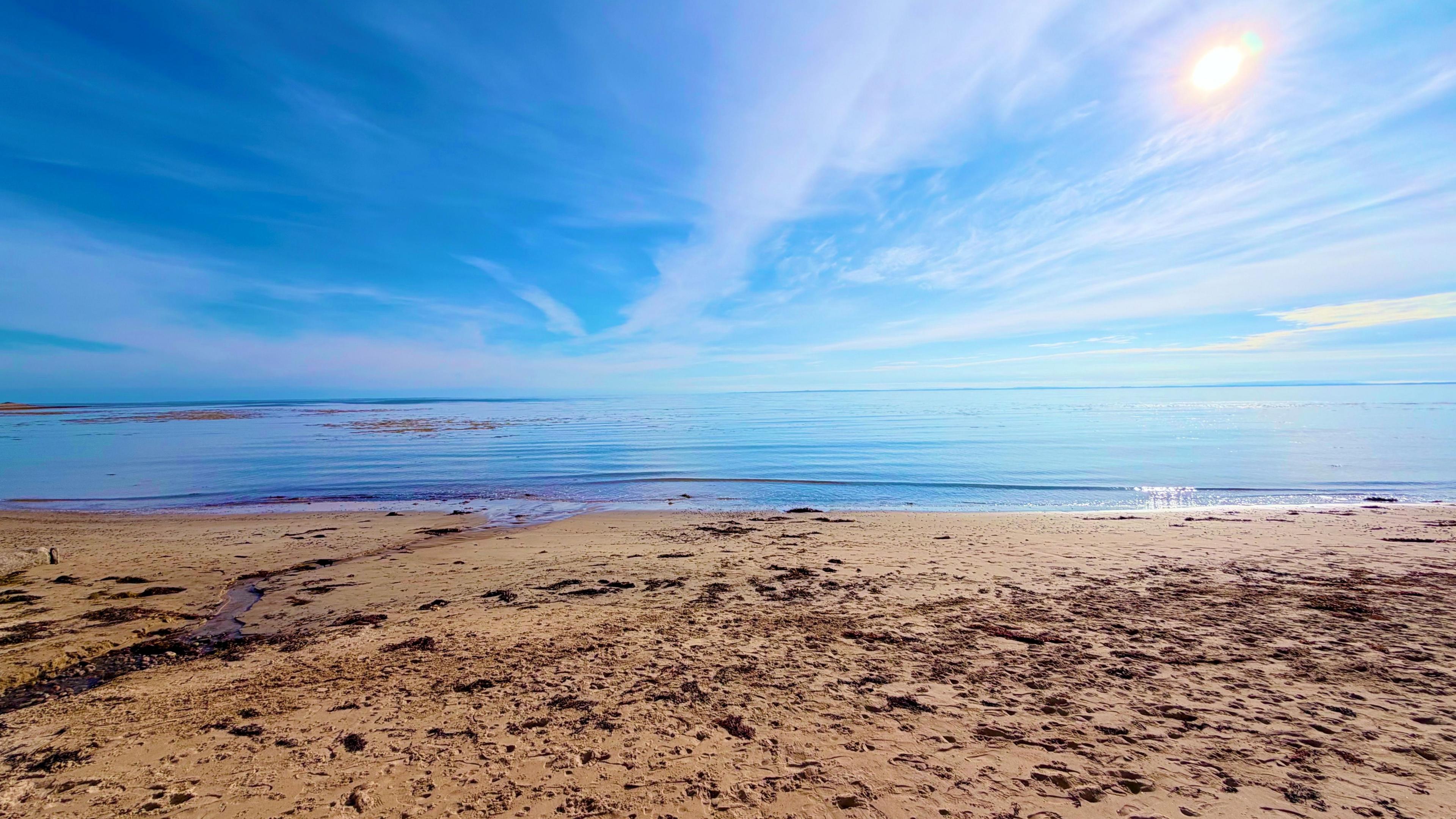 A sandy beach, in front of blue sea, on a sunny day
