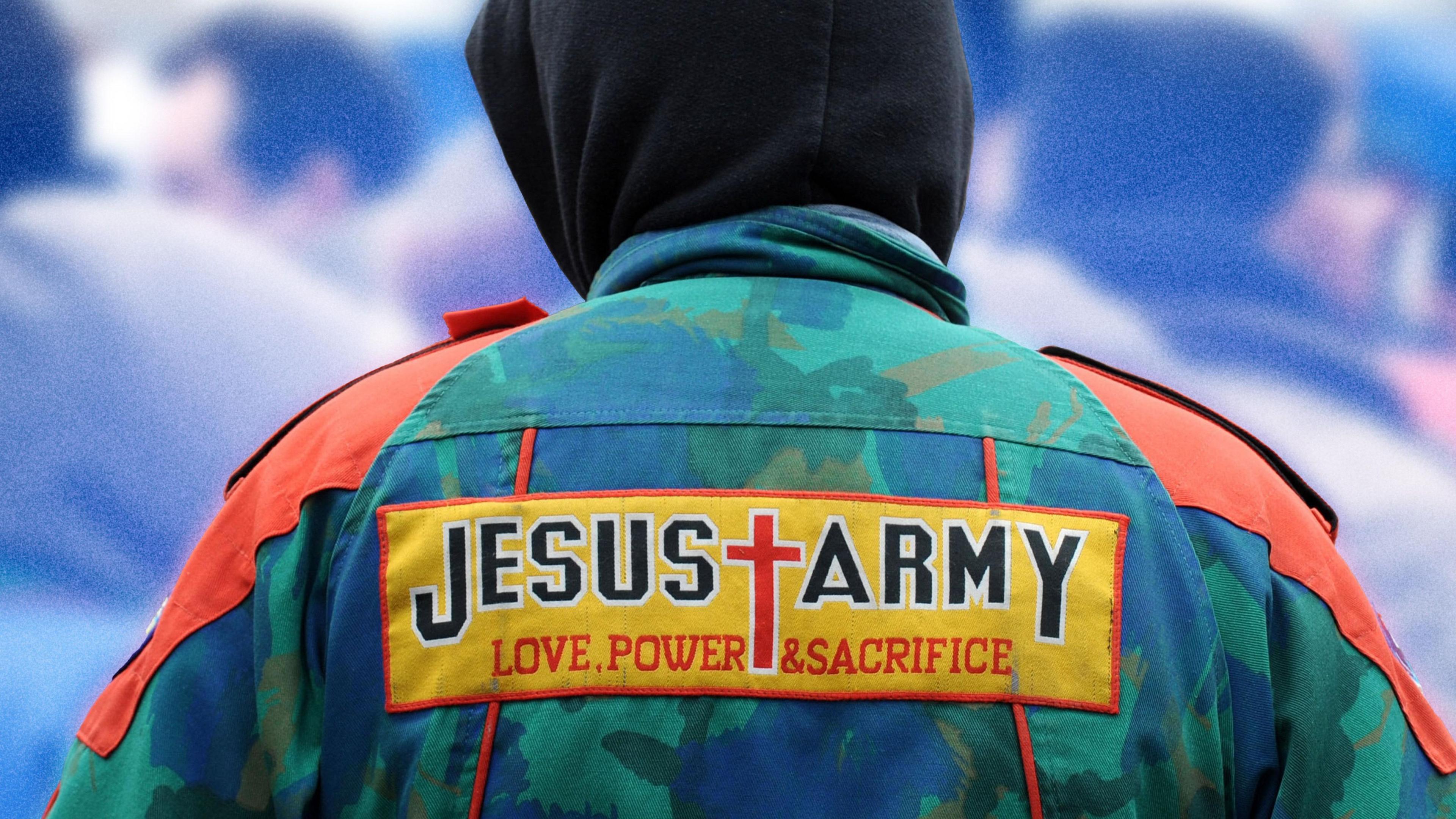 A person facing away from the camera wears a green and blue army print jacket with a Jesus Army patch on the back