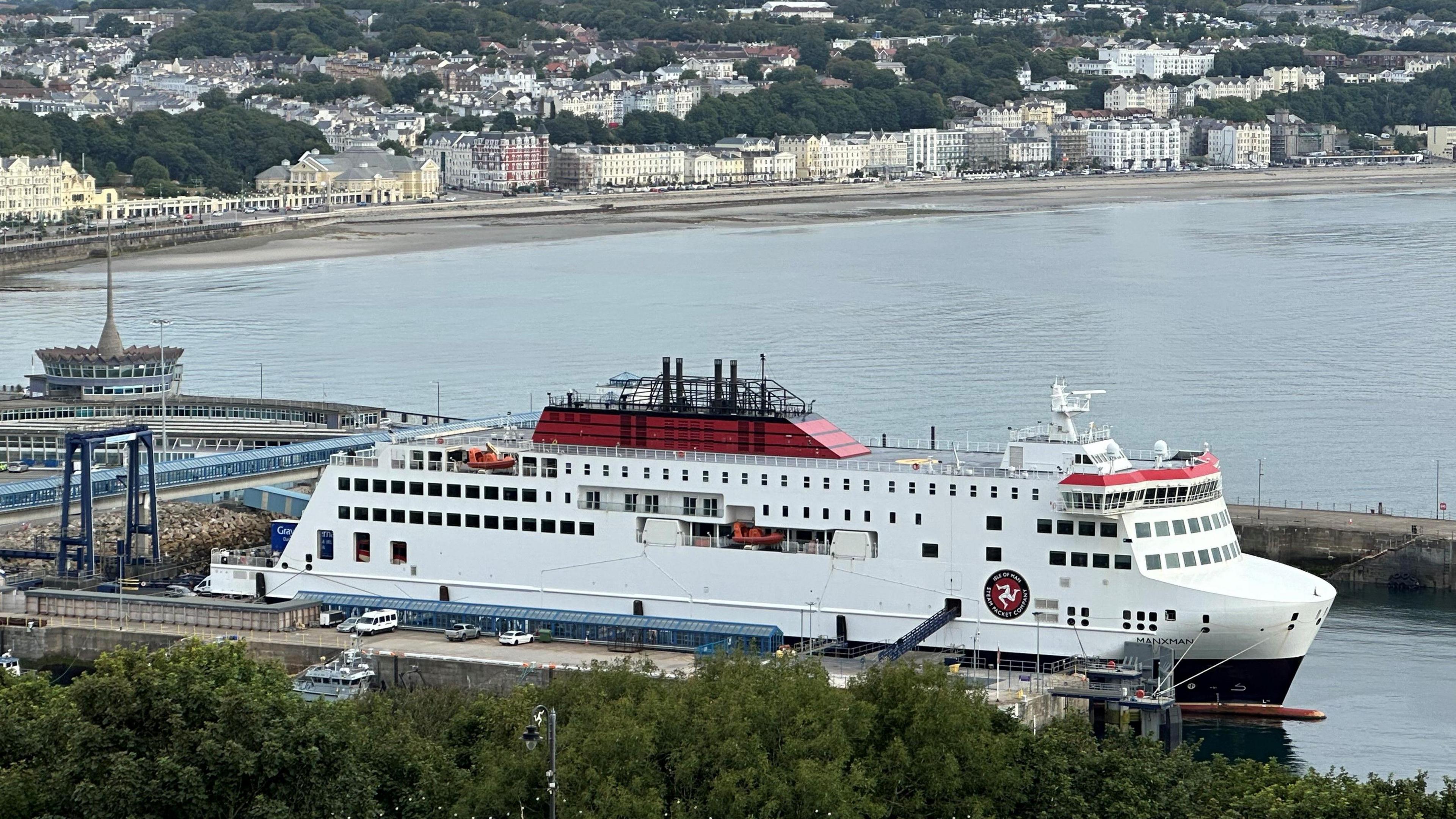 The Manxman ferry, which is red white and black and has the Steam Packet Company's logo featuring the three legs of Mann on the side. It is moored in Douglas Harbour.