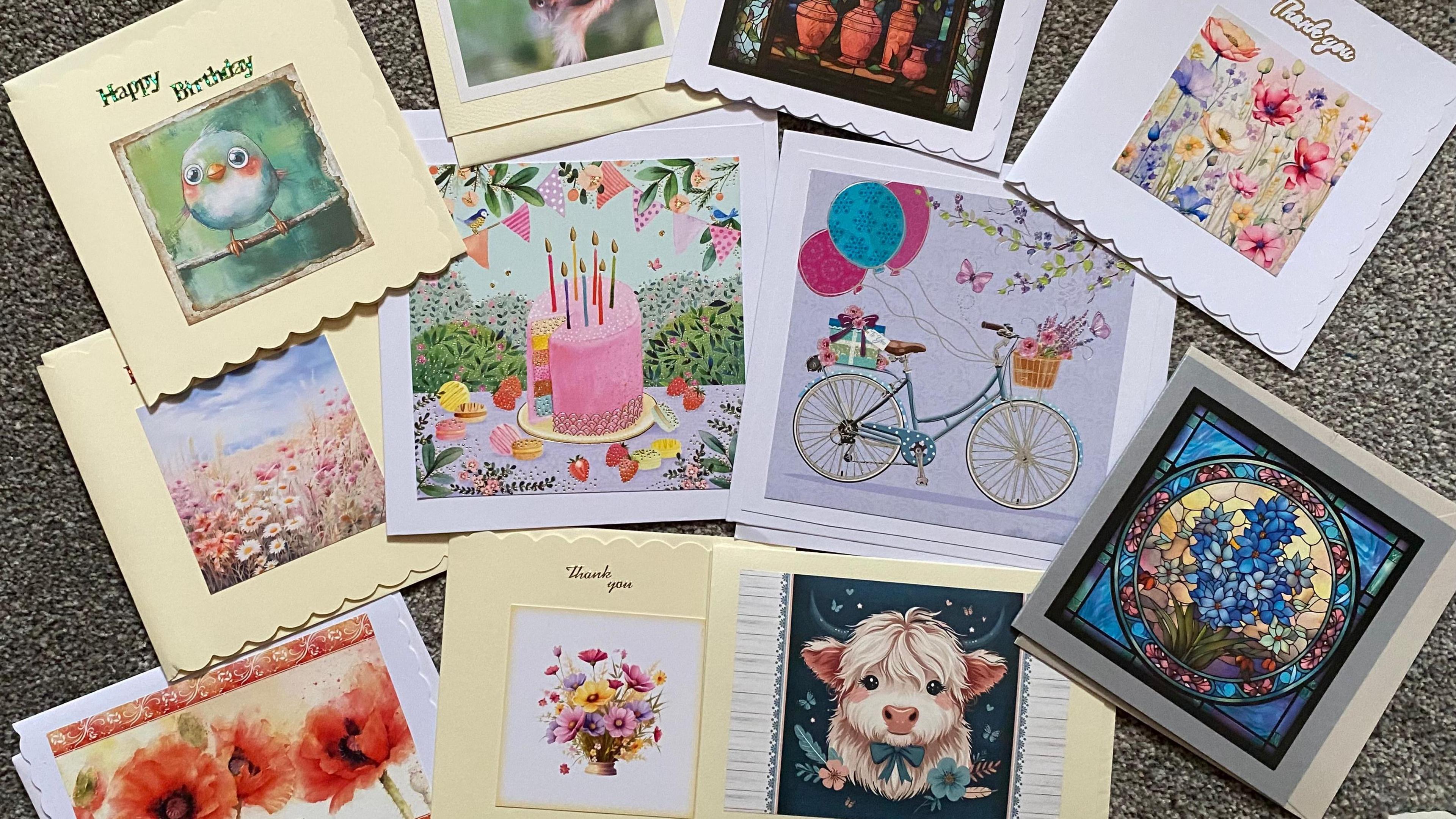 A selection of 11 birthday cards, depicting cakes, birds, bicycles and stained glass windows.