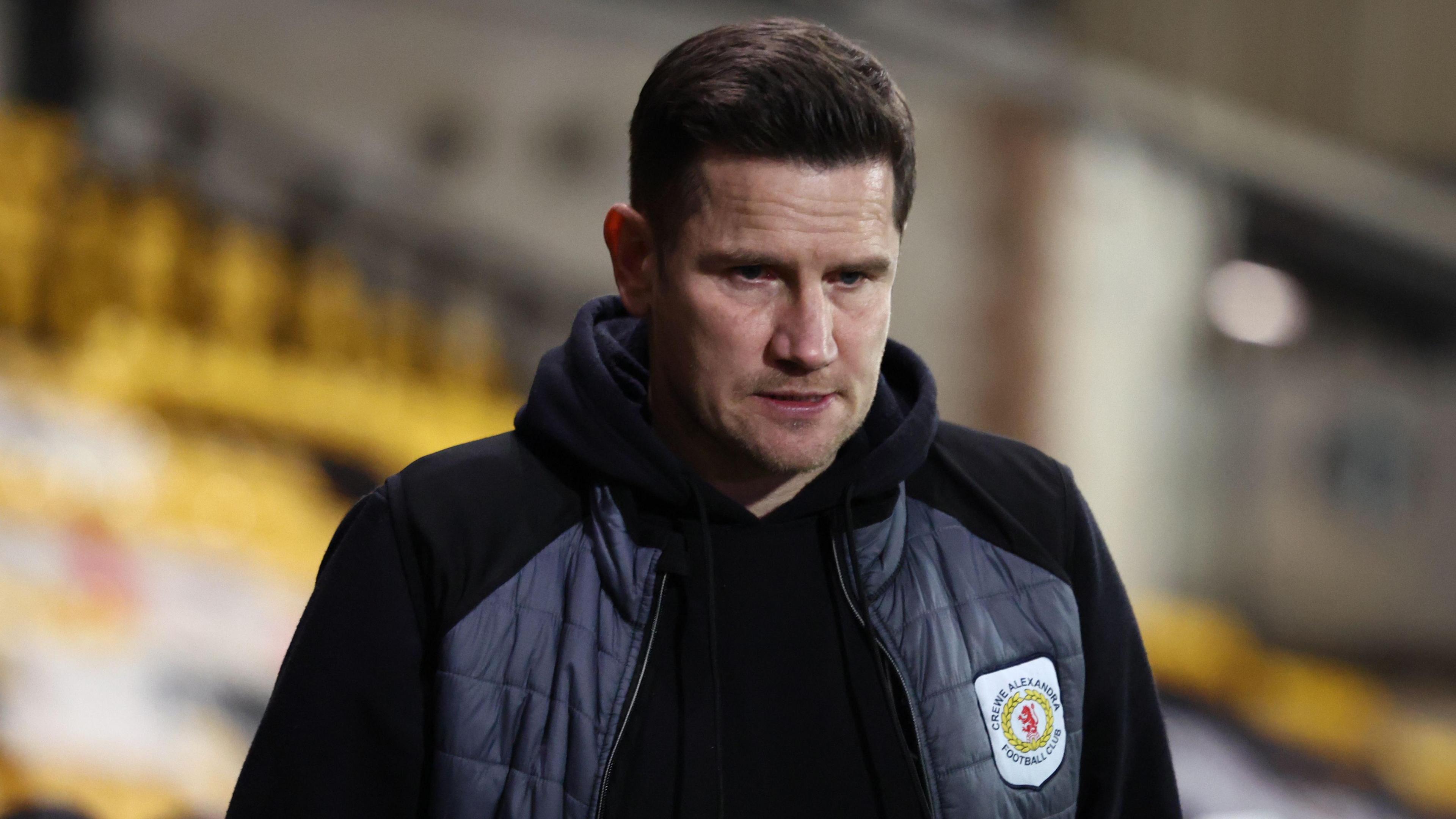 Crewe Alexandra manager Lee Bell stares towards the ground as he walks towards the dressing room after a match