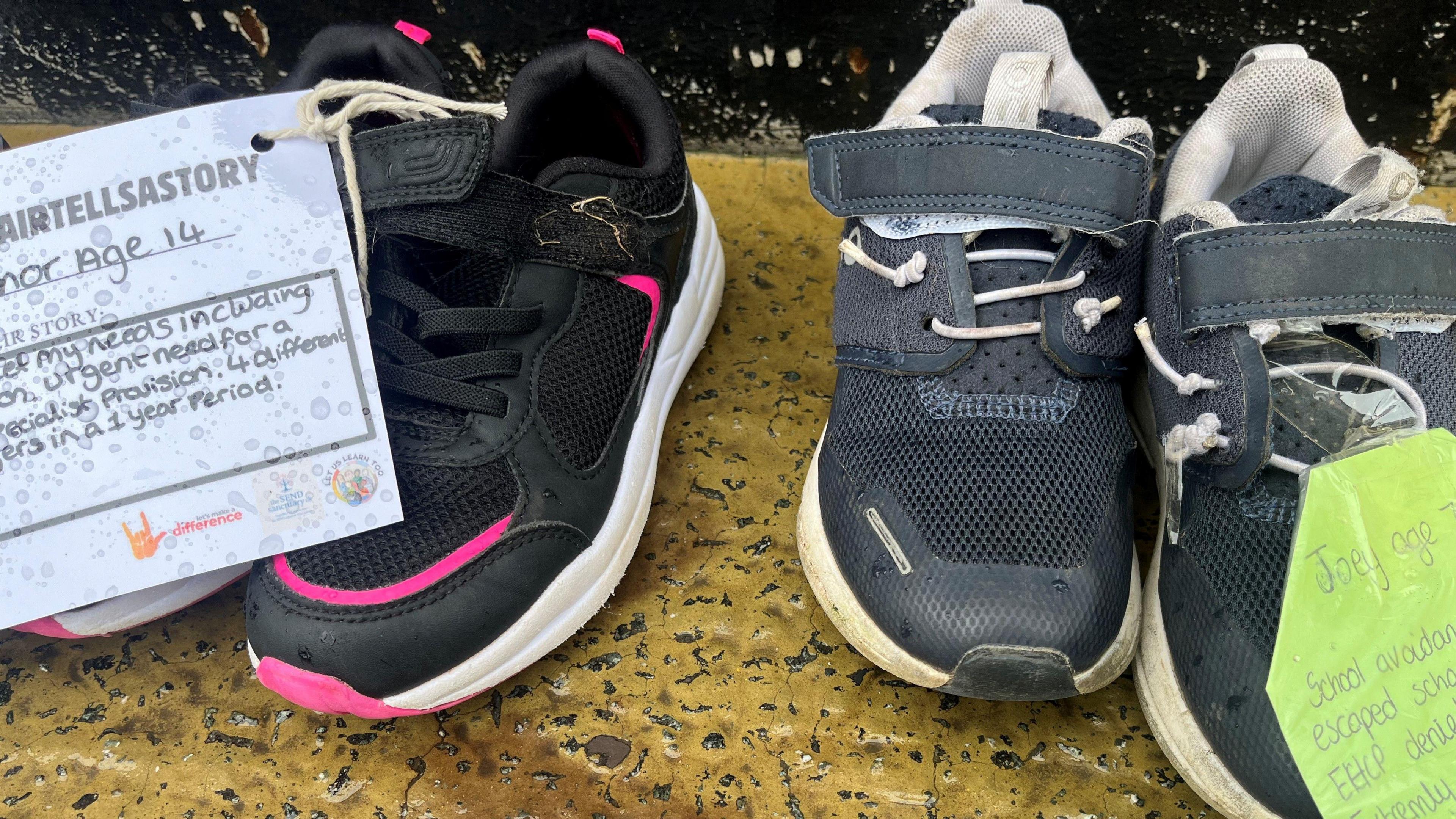 Trainers with attached notes telling the stories of the child they belonged to.